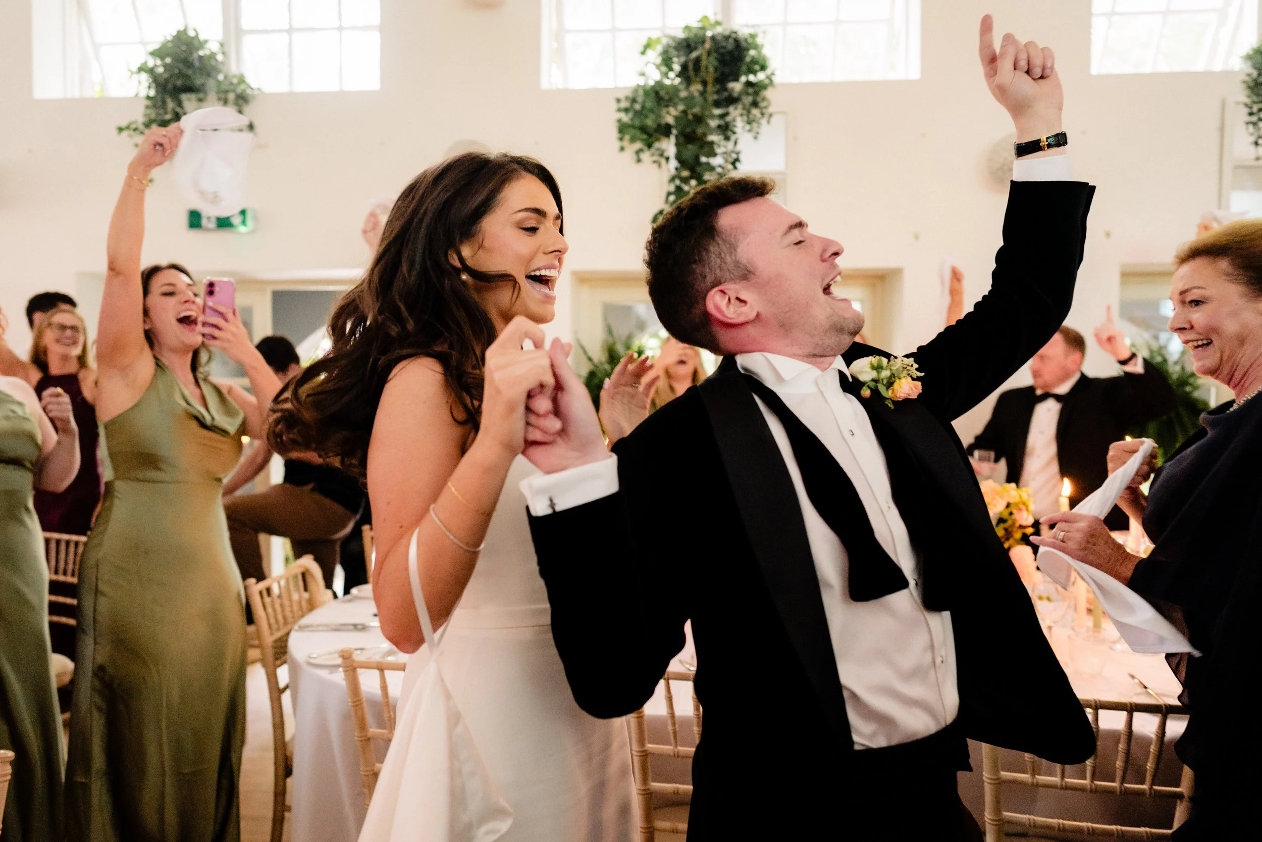 The excited entrance of the bride and groom captured documentary style in this wedding photography of a black tie wedding at Gloster House