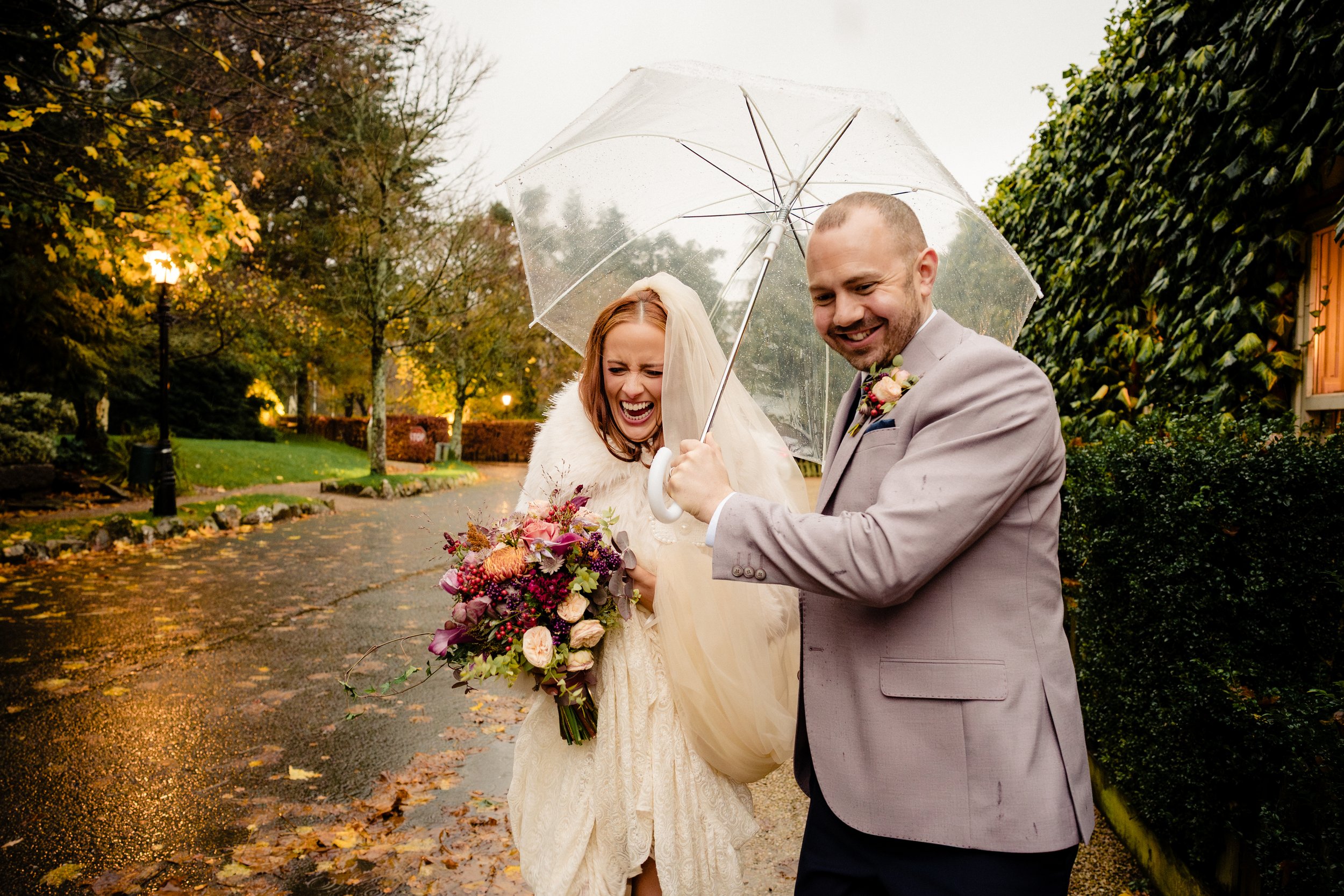 A newlywed couple shelter under an umbrella during their rainy day wedding in BrookLodge Hotel