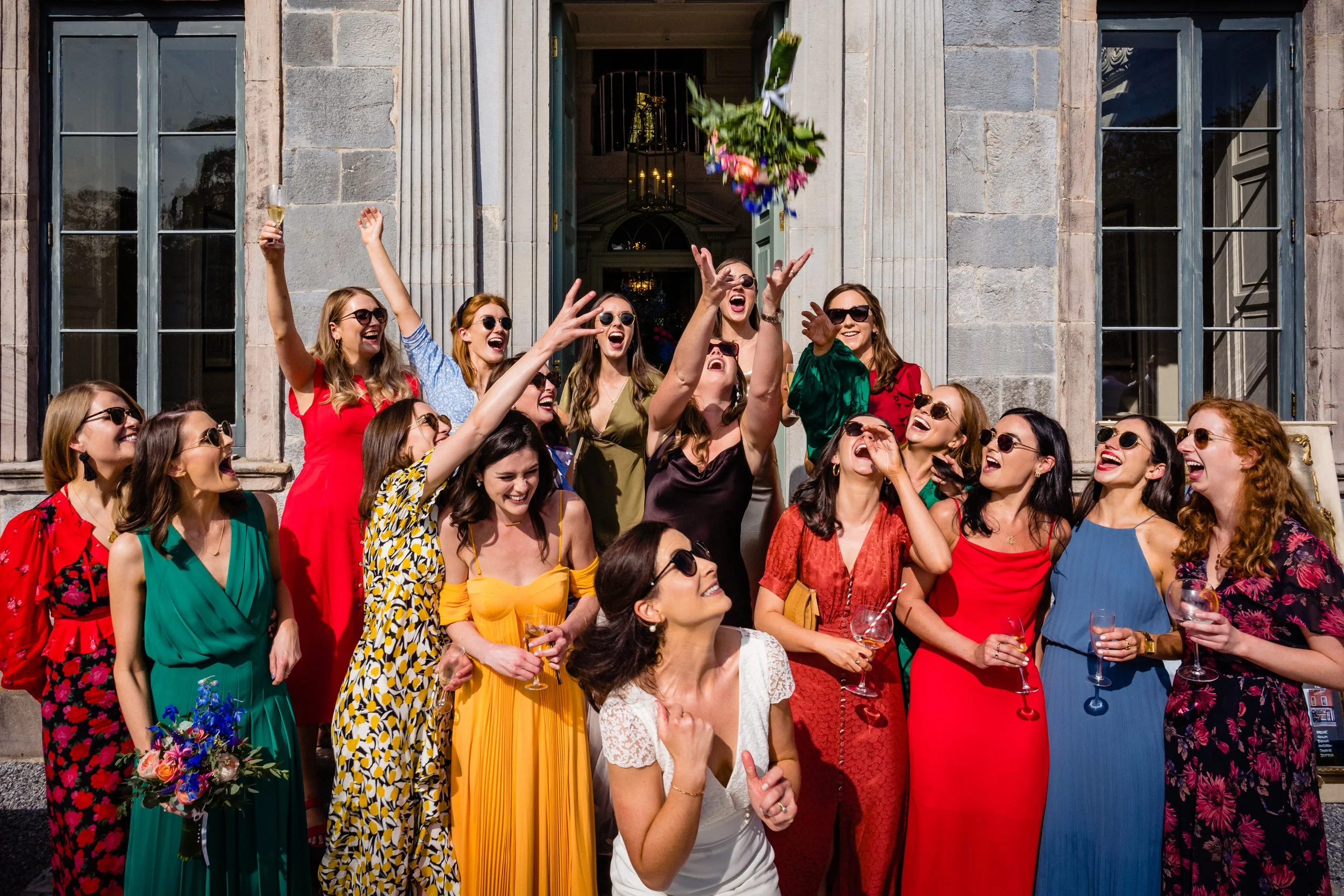 Gloster House wedding photographer captures the moment of the bride throwing her bouquet to all her friends at her outdoor drinks reception on the terrace at Gloster House