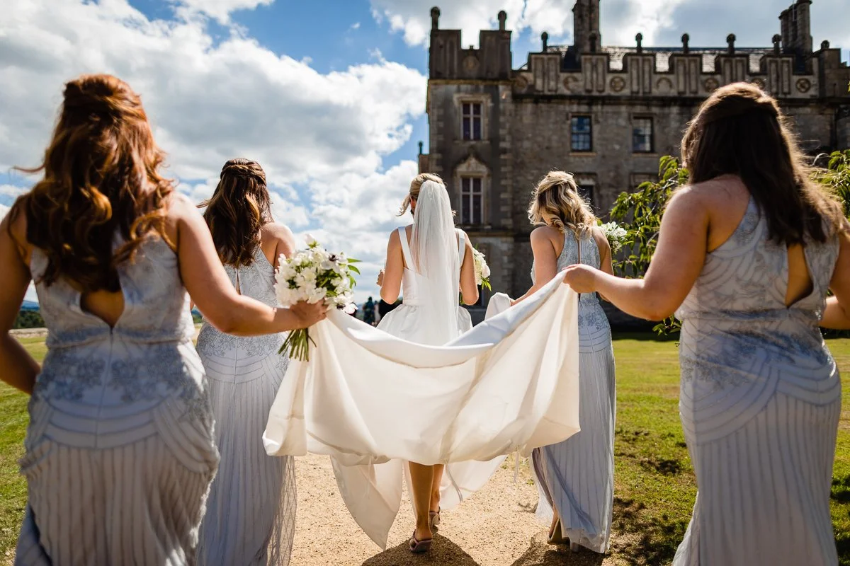 wedding photograph of Bridesmaids holding brides dress walking to borriss house