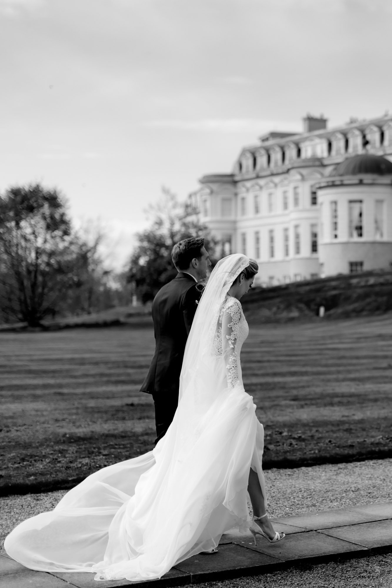 A black and white wedding photograph of an elegant couple in black tie with the K Club as the backdrop
