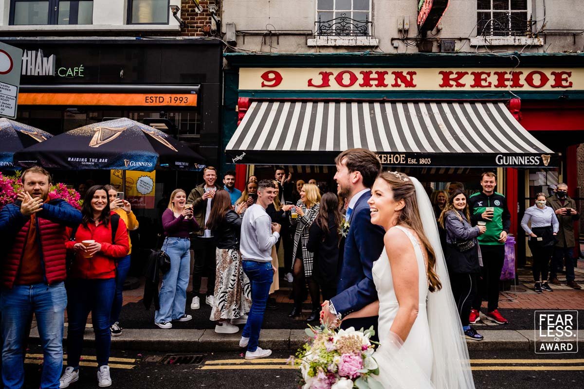 A Dublin wedding photographer captures the moment that the bride and groom pass Kehoes pub to cheering crowds during their Dublin city centre wedding