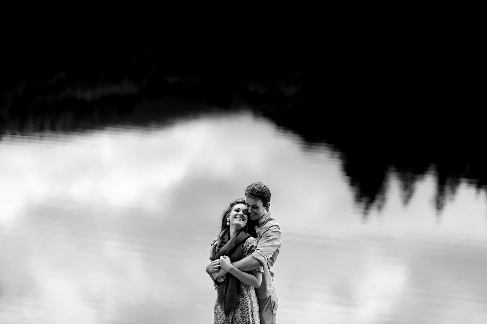 An engagement photoshoot image of a couple against a lake in Glandalough, Wicklow, Ireland