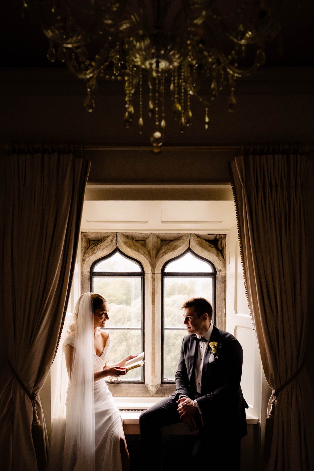 A wedding photograph of a bride and groom reading their private vows to each other in the window at Kilkea Castle
