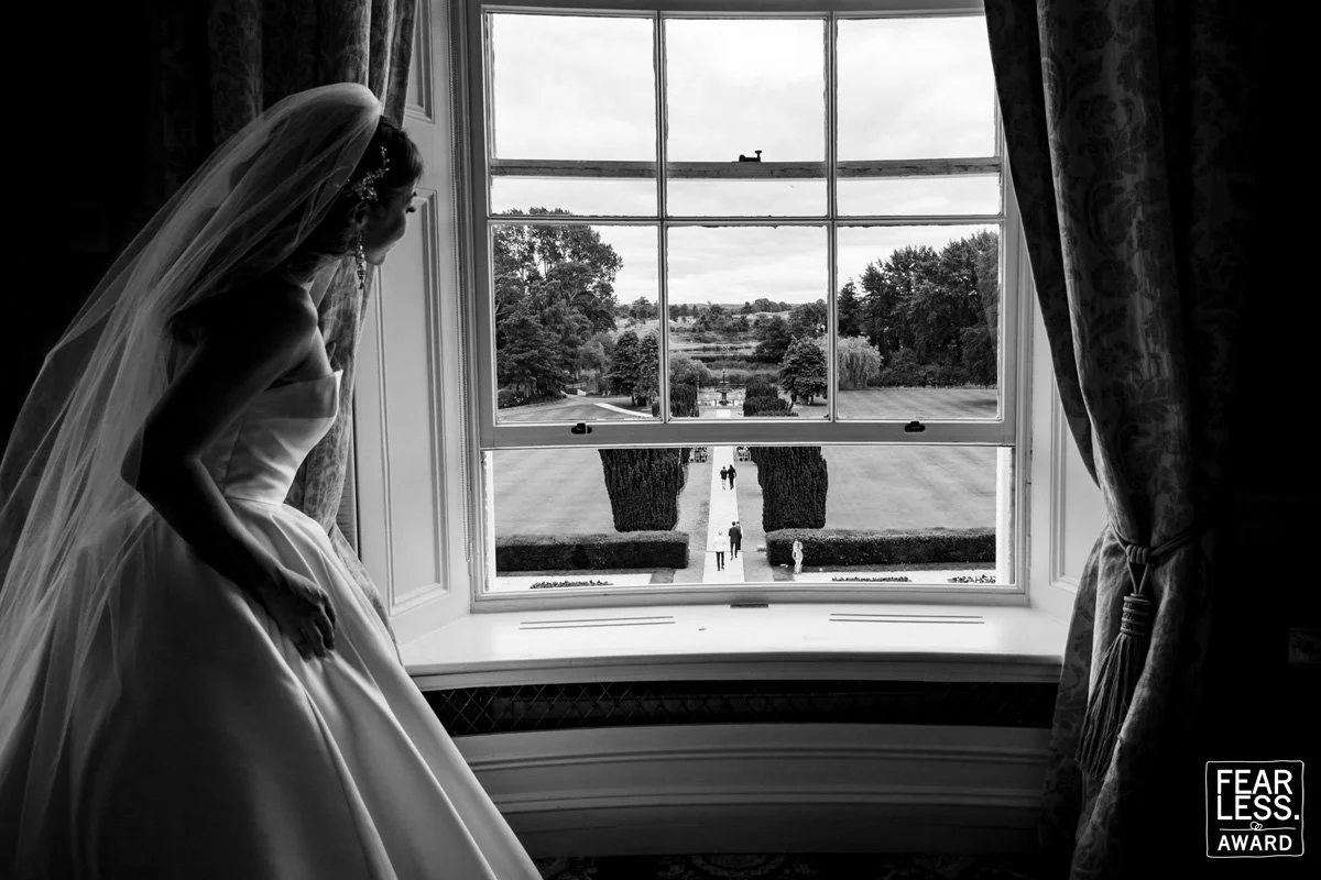 Elegant documentary style wedding photography of a bride peeking out at her outdoor ceremony in the K Club Ireland