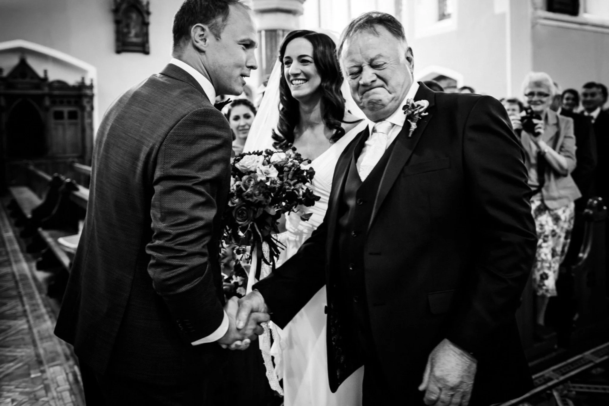 black and white photo of father of bride in a chruch getting emotional