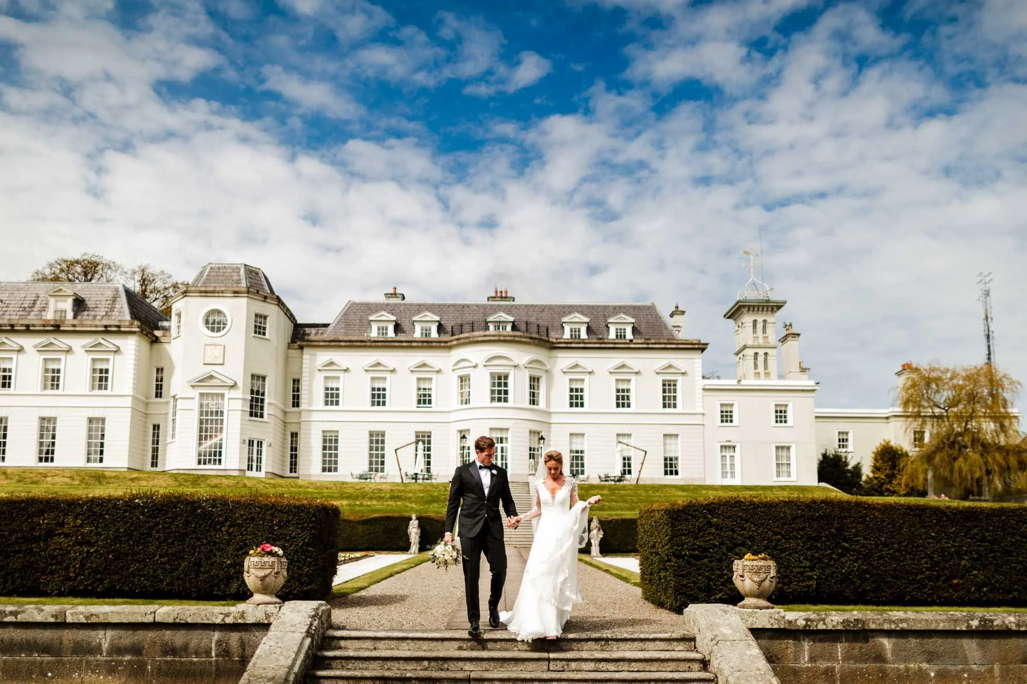 A classic wedding photograph of the bride and groom in black tie walking away from the K Club
