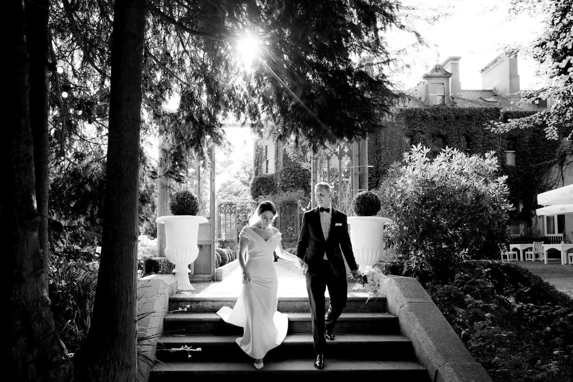 A natural looking black and white photograph of an elegant bride and groom walking to dinner at Tinakilly House