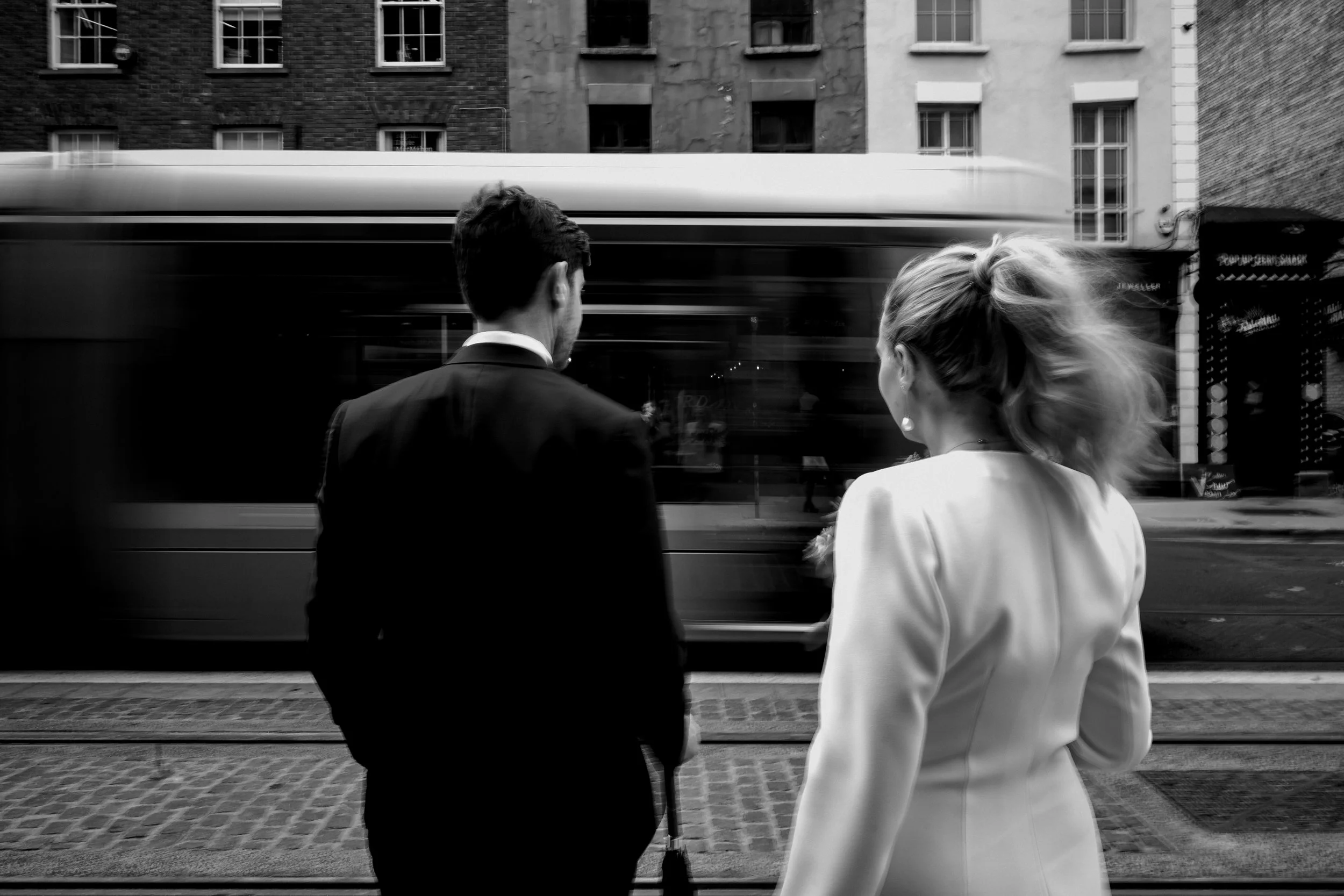 At a small Dublin city centre wedding the bride and groom wait to cross Dawson St and the photographer creates motion blur of the Luas going by