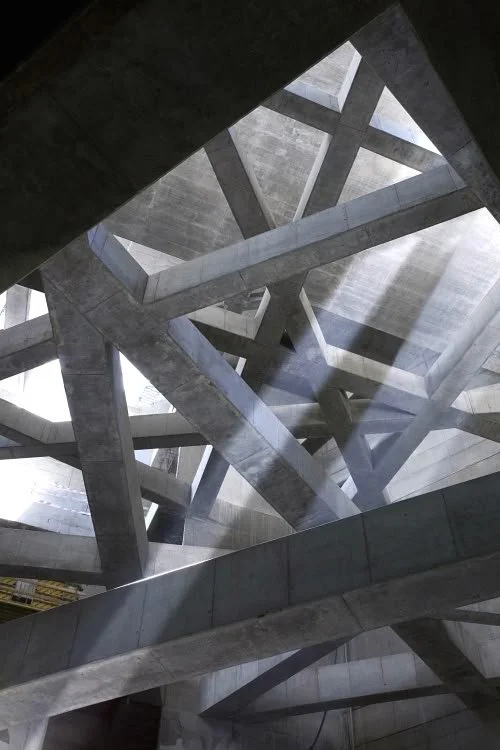 View of a modern concrete architectural ceiling with geometric patterns, beams, and skylights.