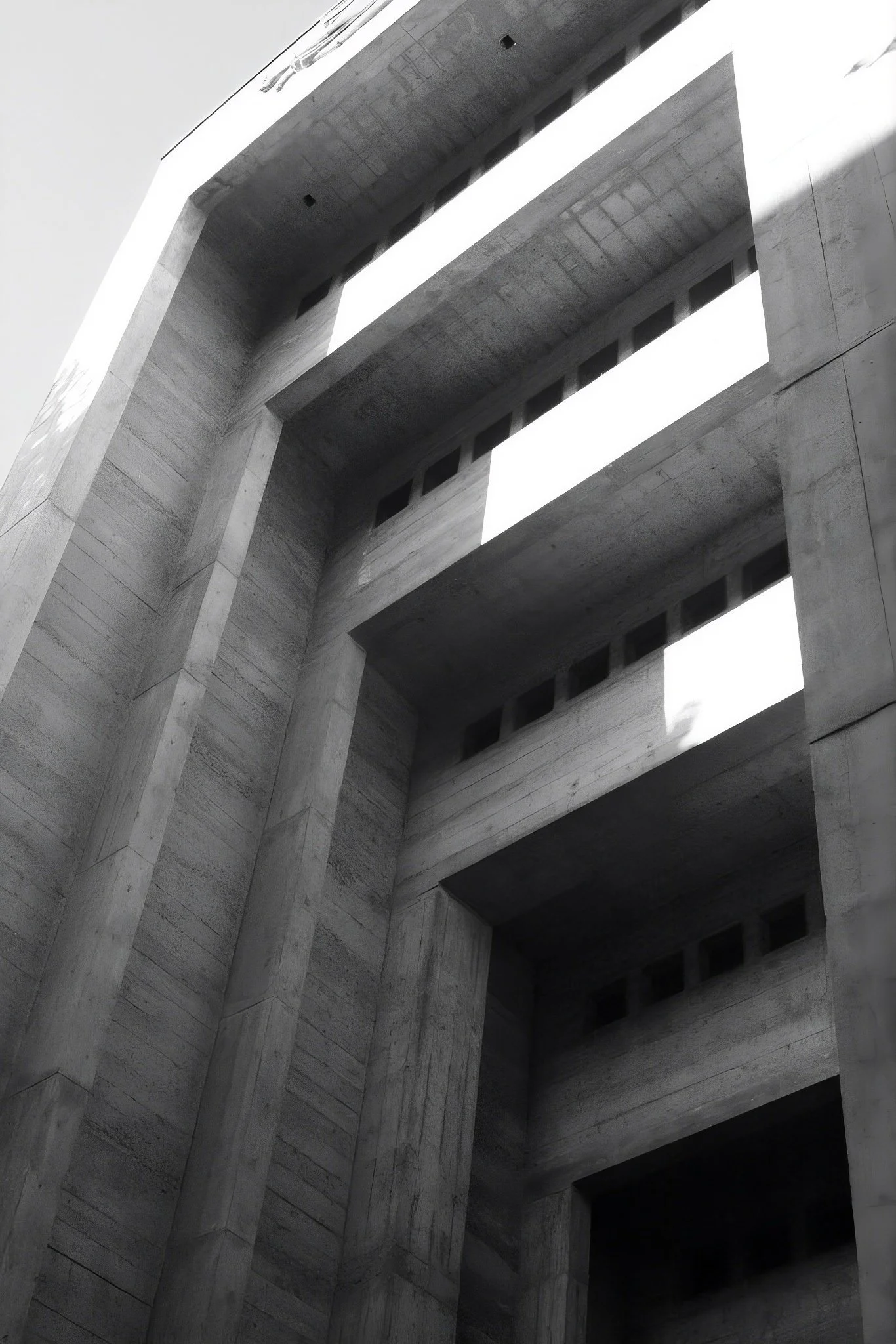 Modern concrete building with large rectangular cutouts and deep shadows, photographed from a low angle.