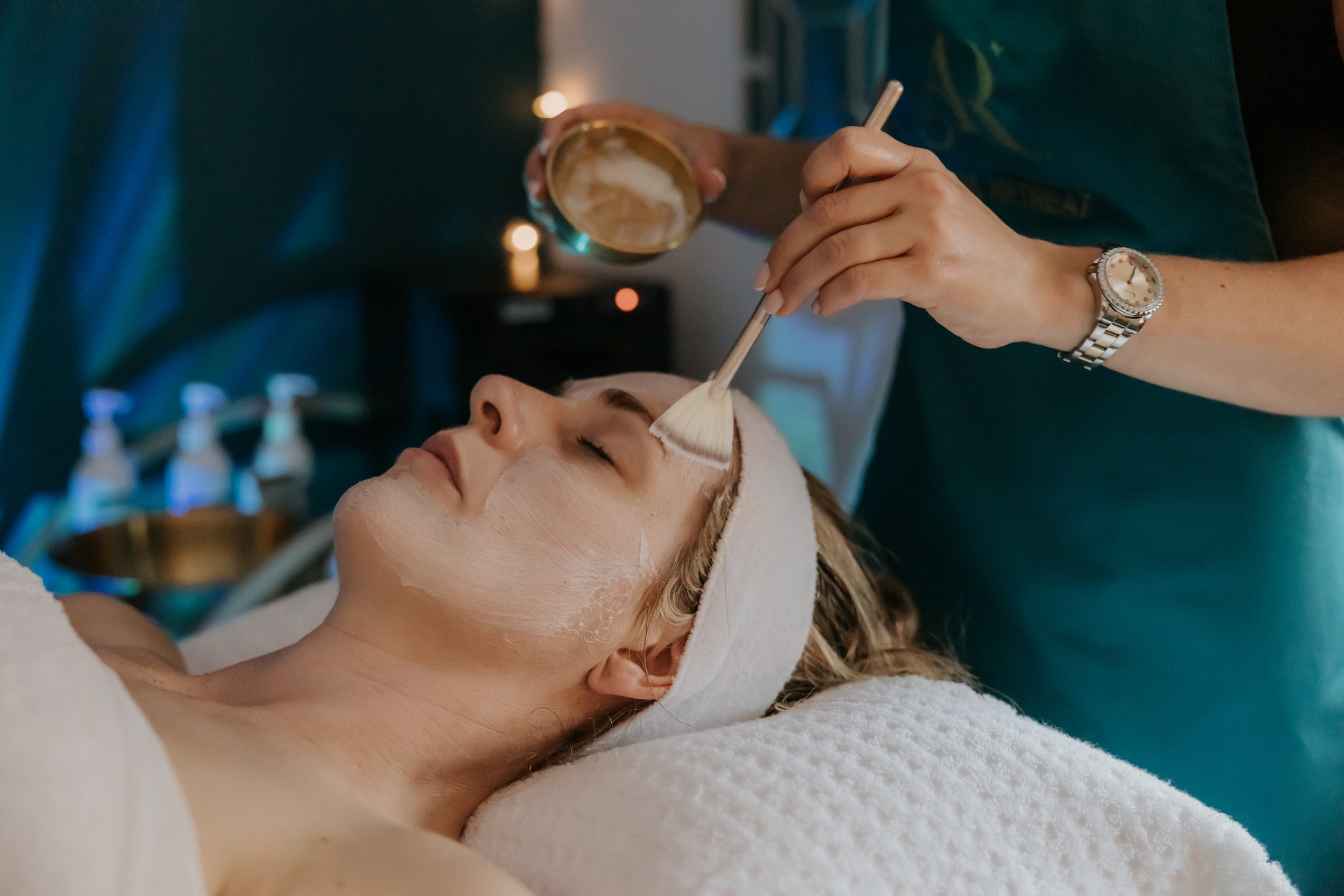 Woman receiving a facial treatment with a brush at the astral retreat salon