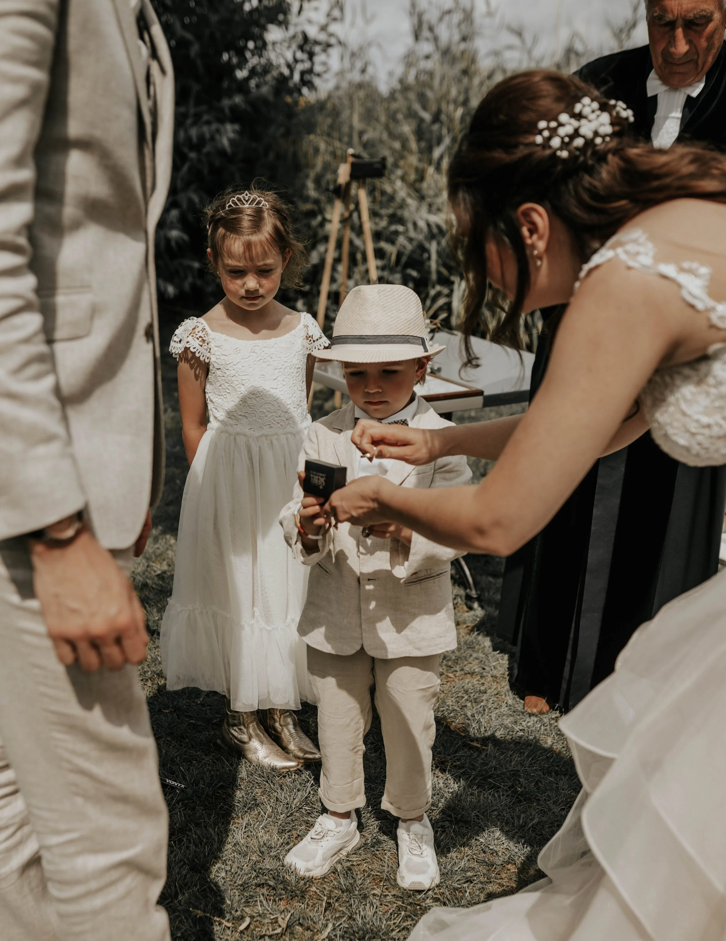 Kinderen en volwassenen tijdens een huwelijk, met kinderen in bruid en heer kostuums, buiten op een zonnige dag.