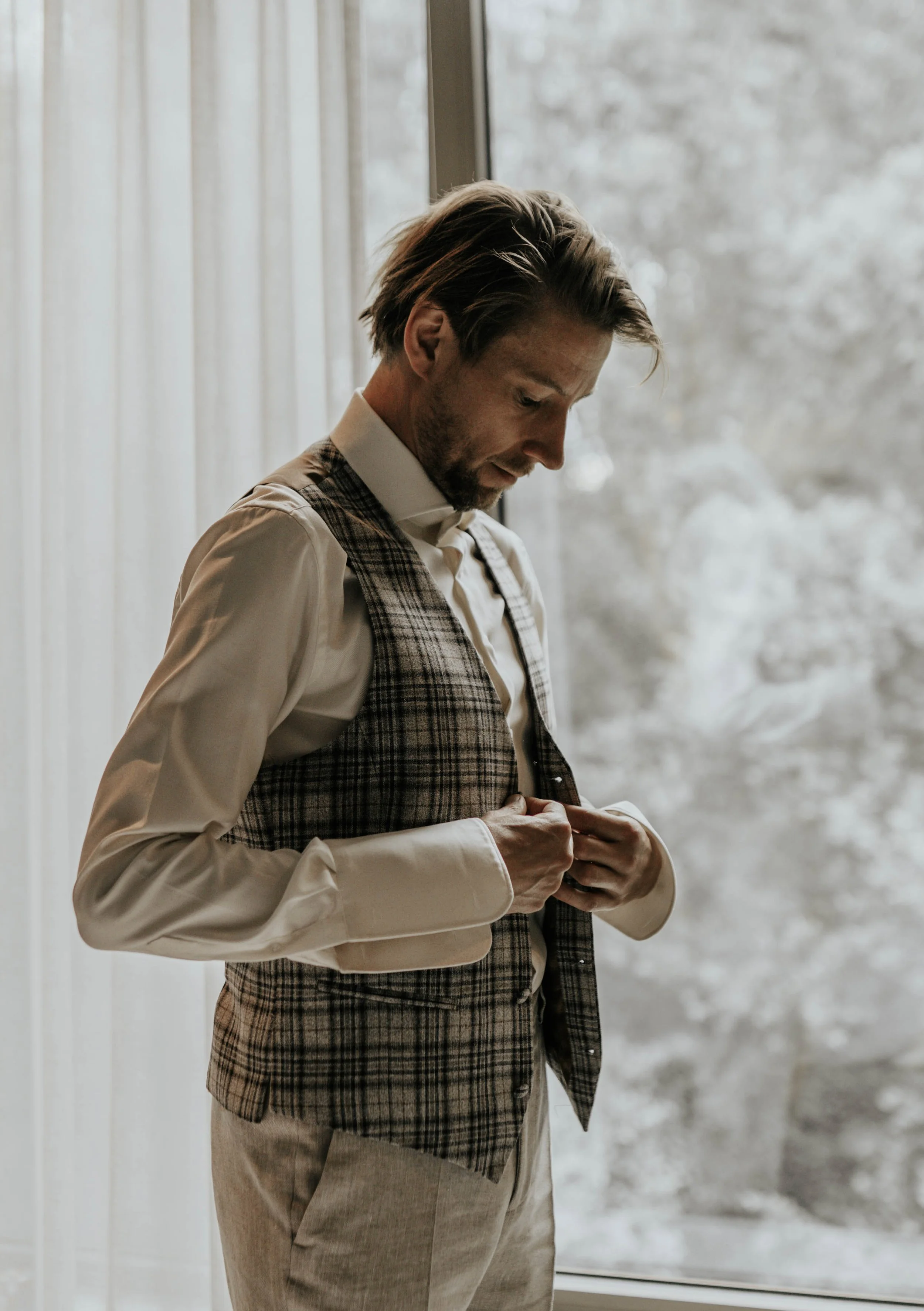 Man in overhemd en broek die zich klaarmaakt voor een formele gelegenheid.
