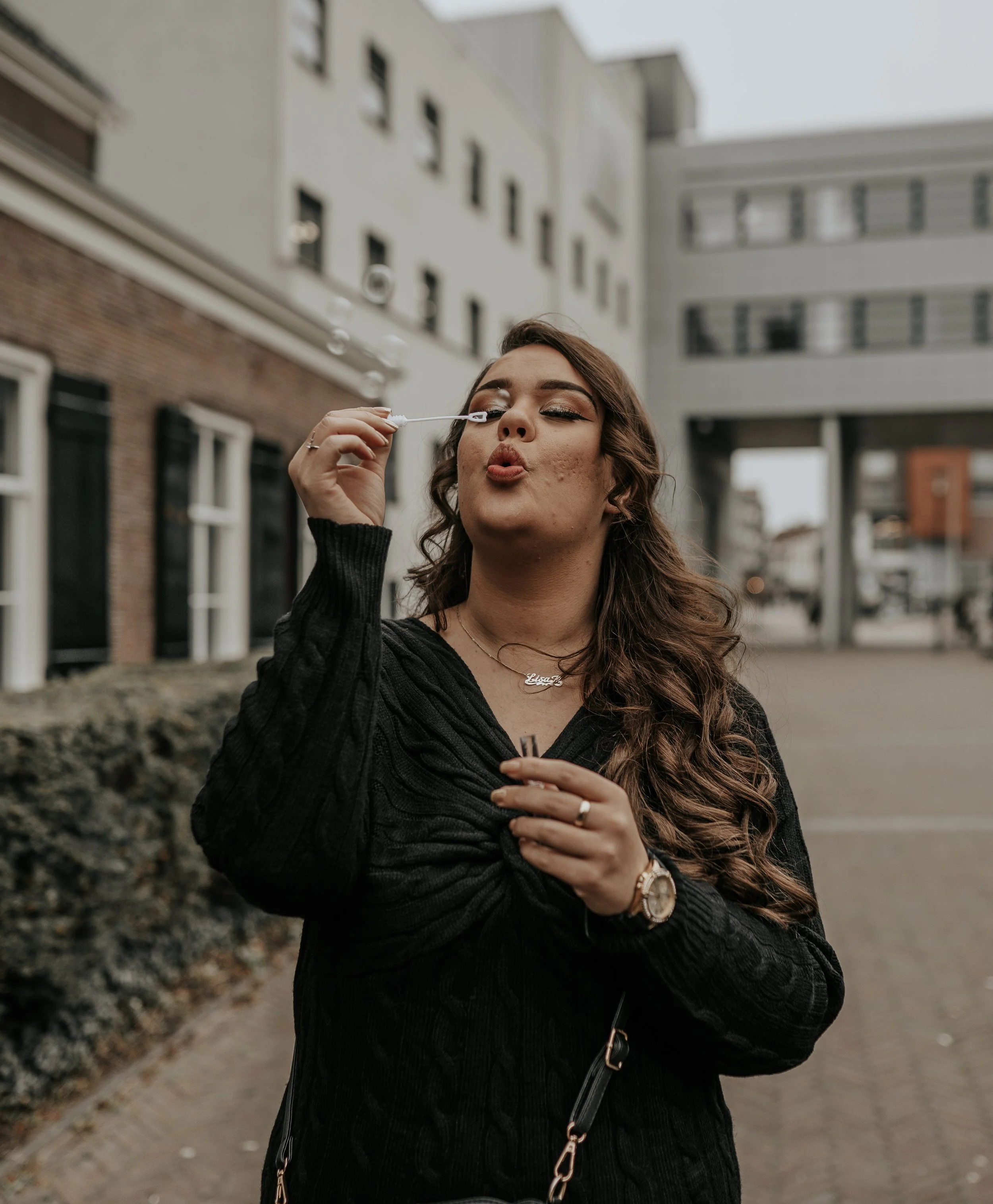 Een vrouw met bruin haar blaast bellen in een stadsomgeving.