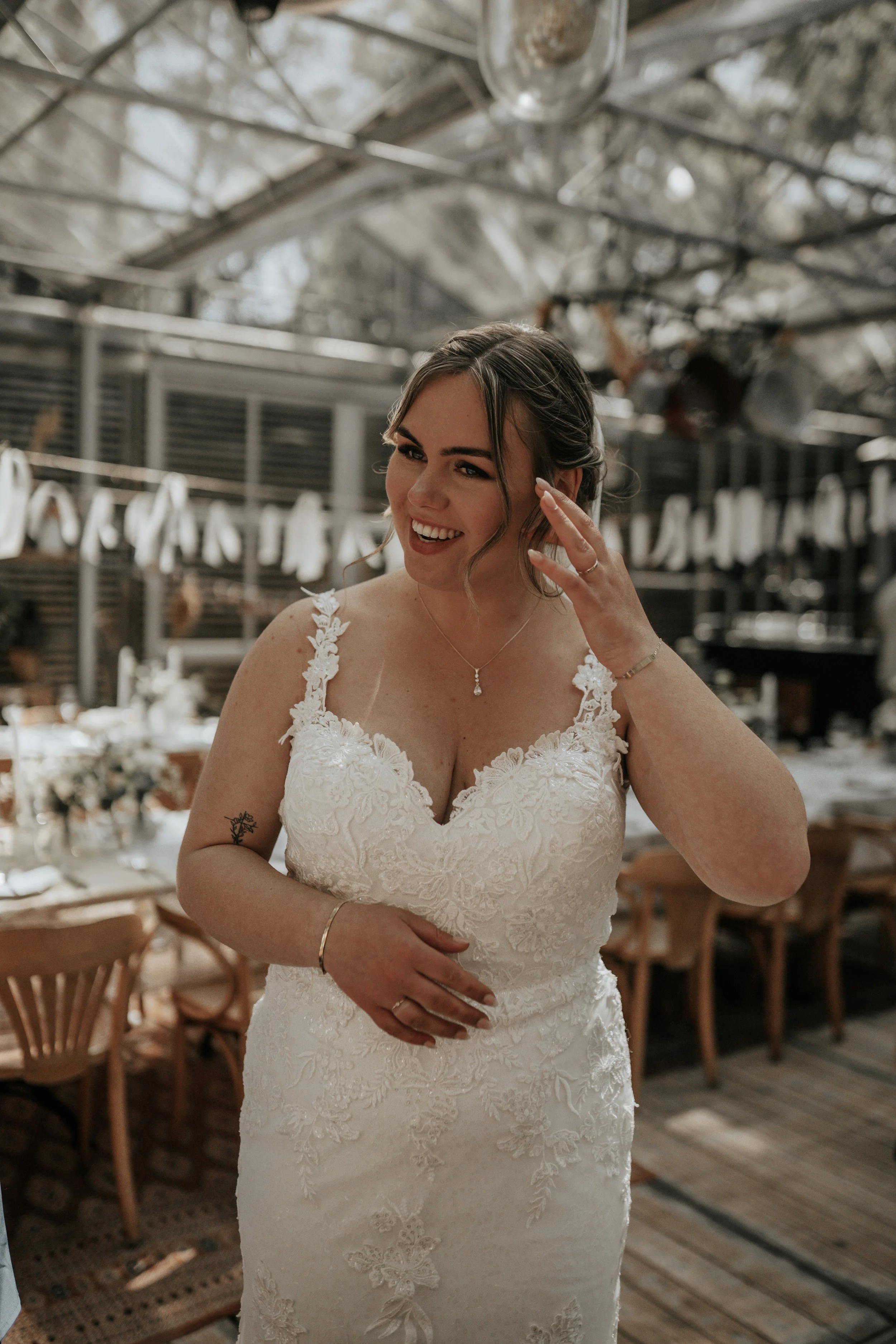 Een lachende vrouw in een witte bruidsjurk in een feestzaal.