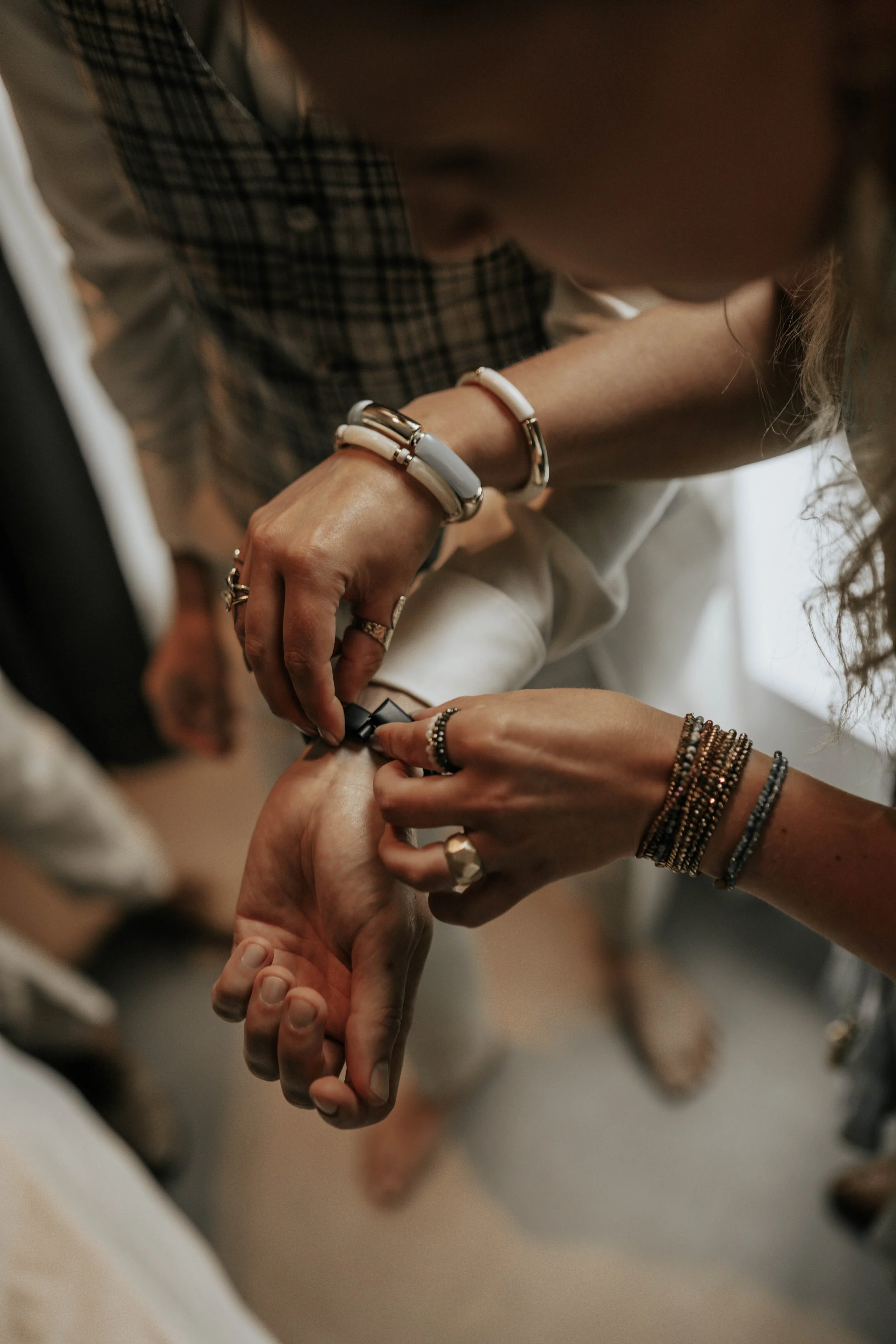 Mensen helpen een polsbandje sluiten tijdens een gebeurtenis, met veel sieraden en een check of het goed vastzit.