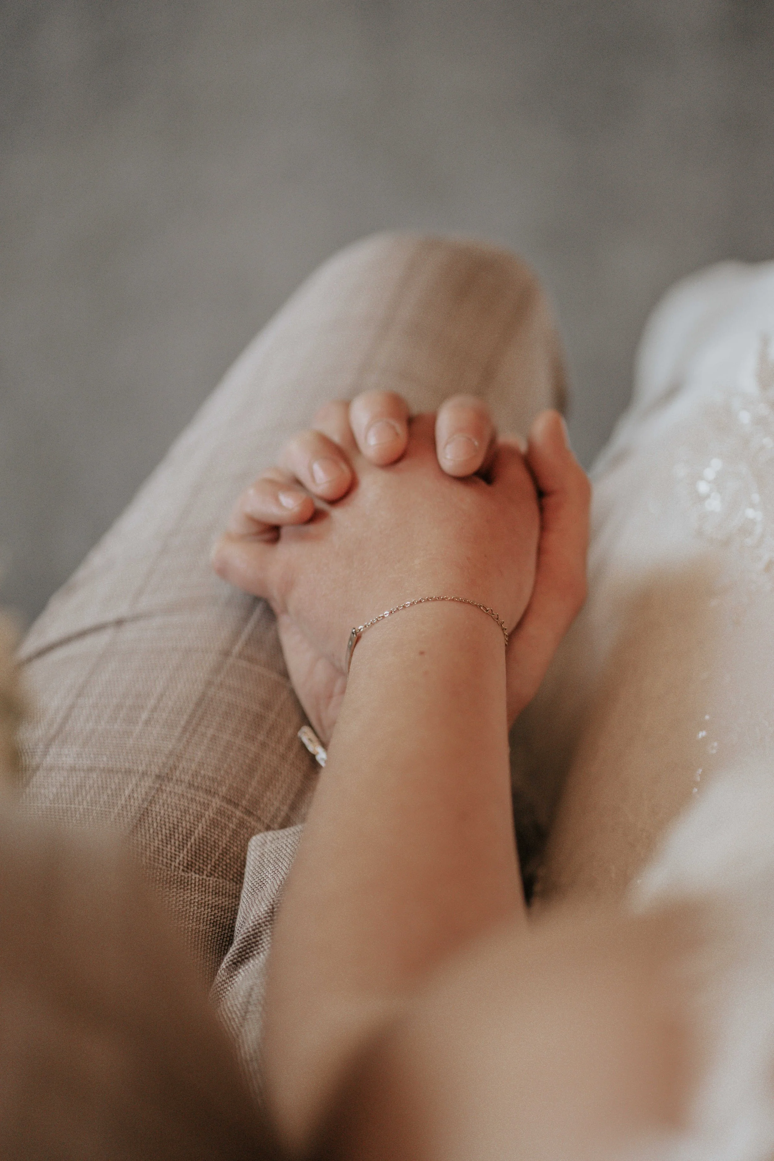 Een close-up van twee mensen die handen vasthouden, waarbij de ene persoon een delicate armband draagt en de achtergrond is vaag.