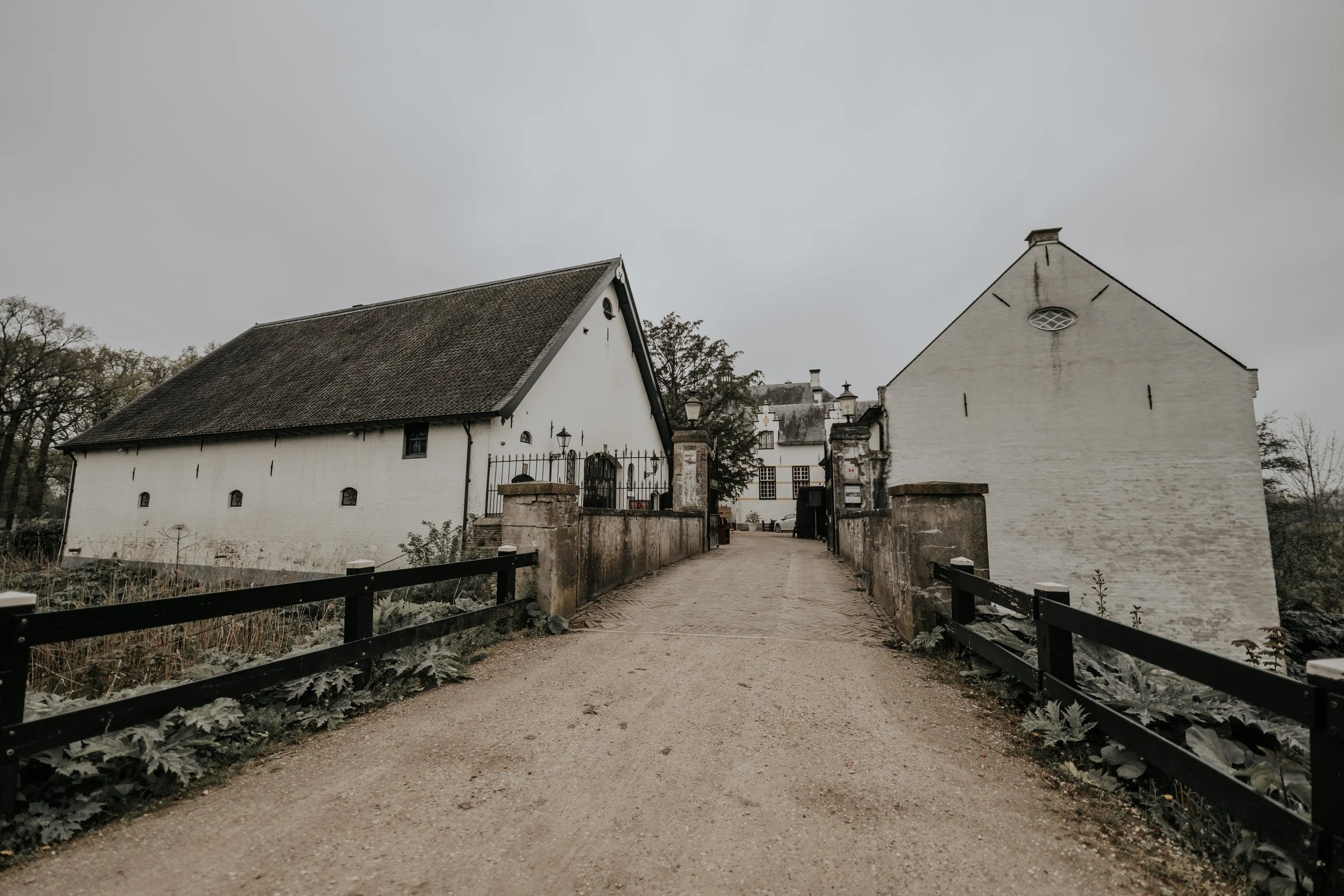 Een smal zandpad tussen witte gebouwen onder een grijze lucht.