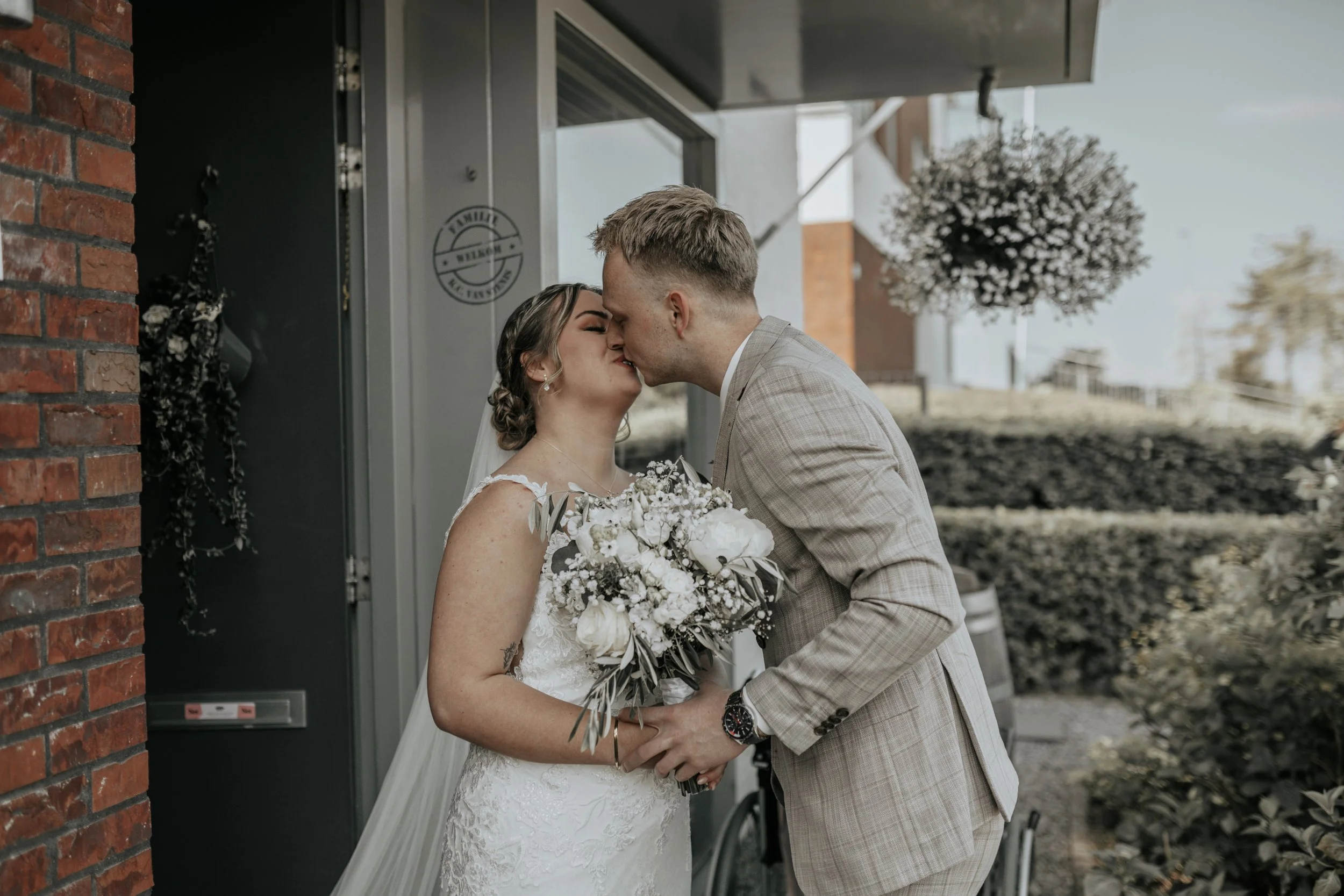 een pasgetrouwd paar dat elkaar kust voor een gebouw