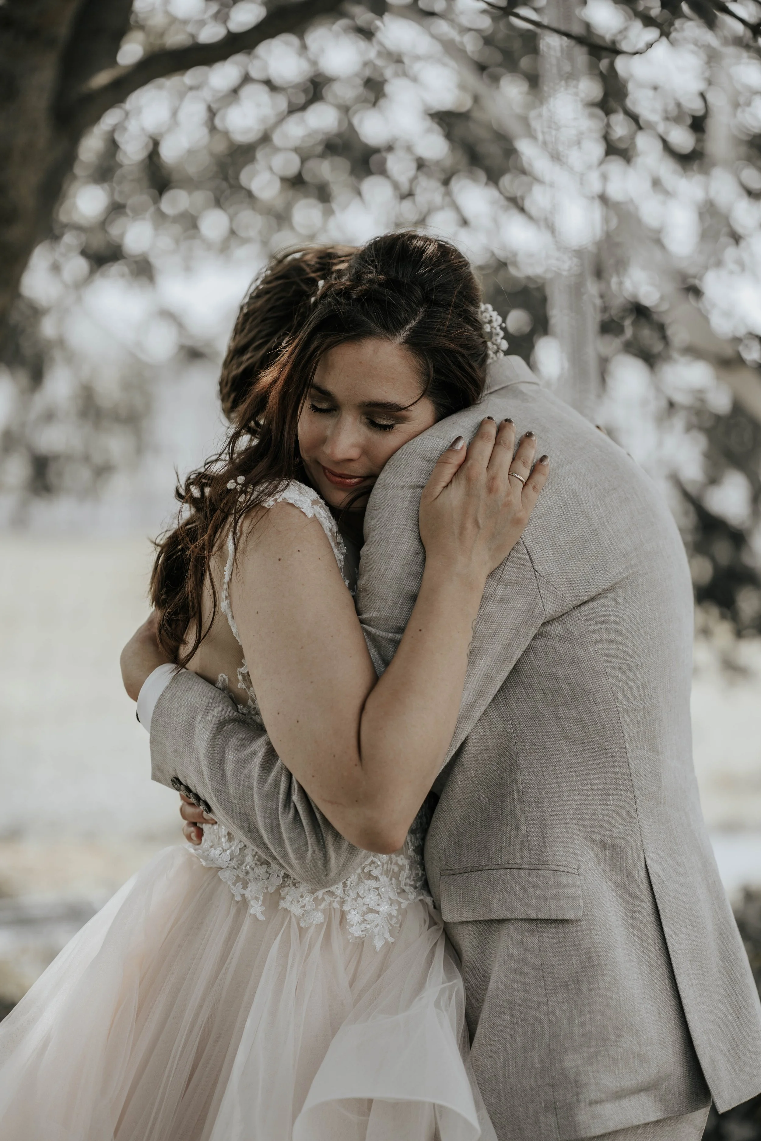 Een bruid en bruidegom die elkaar omarmen tijdens hun huwelijk in een natuurlijke omgeving.