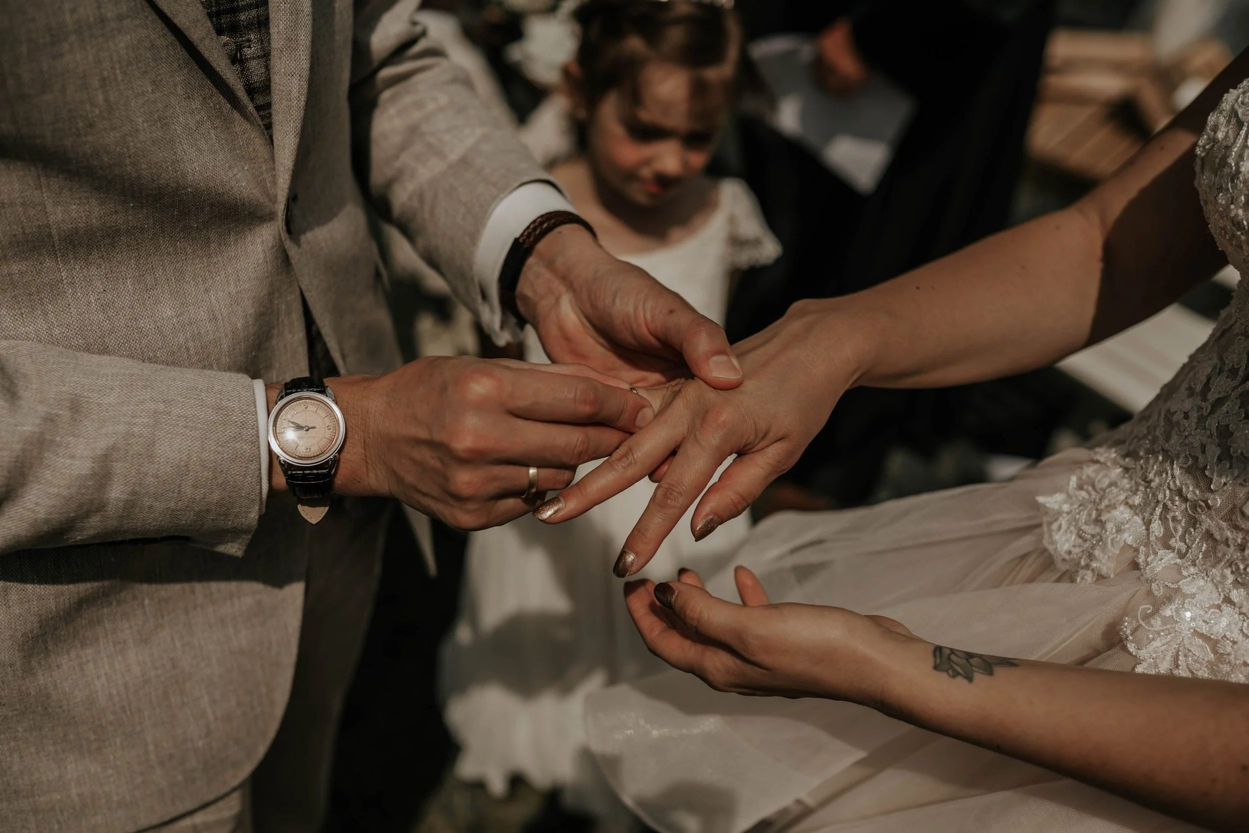 Een man en vrouw die elkaar vasthouden tijdens een huwelijksceremonie, met een kind in de achtergrond.