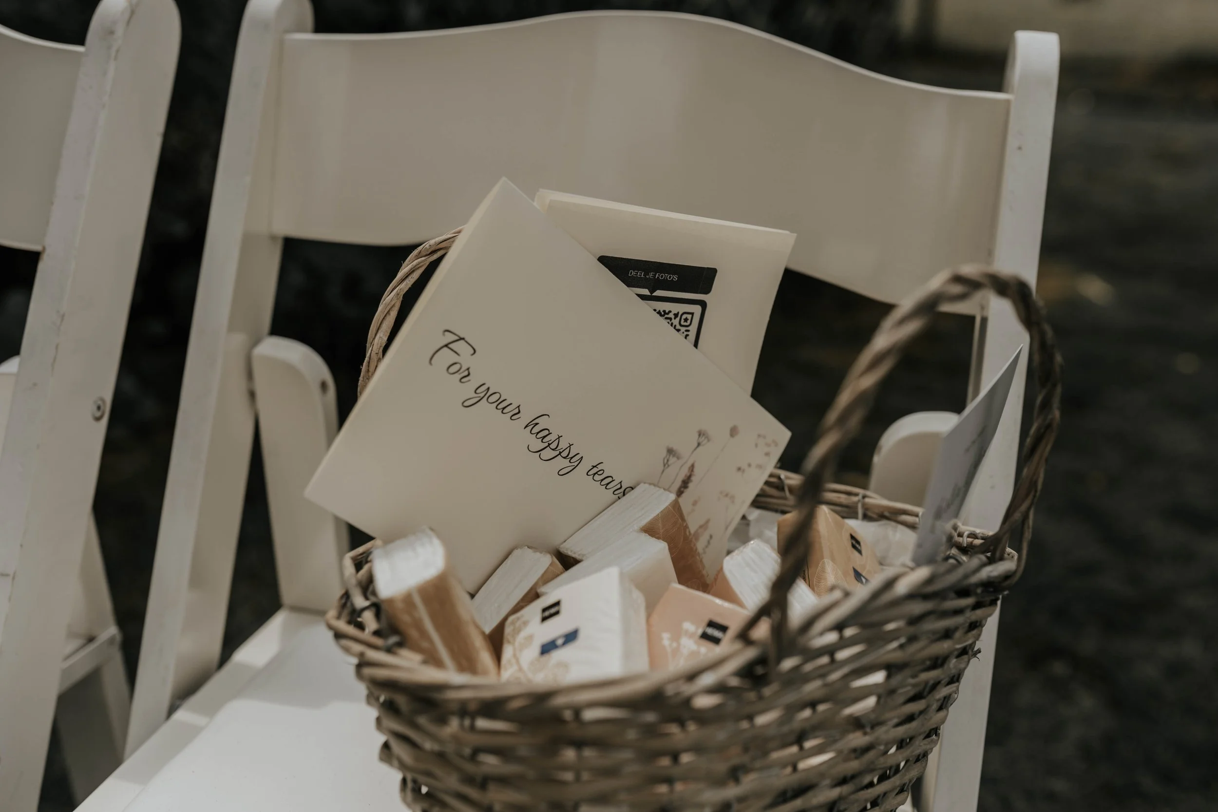 Een mand met papieren kaarten en pakjes, op een witte stoel, met een kaart met de tekst 'Voor jouw gelukkige herinneringen'