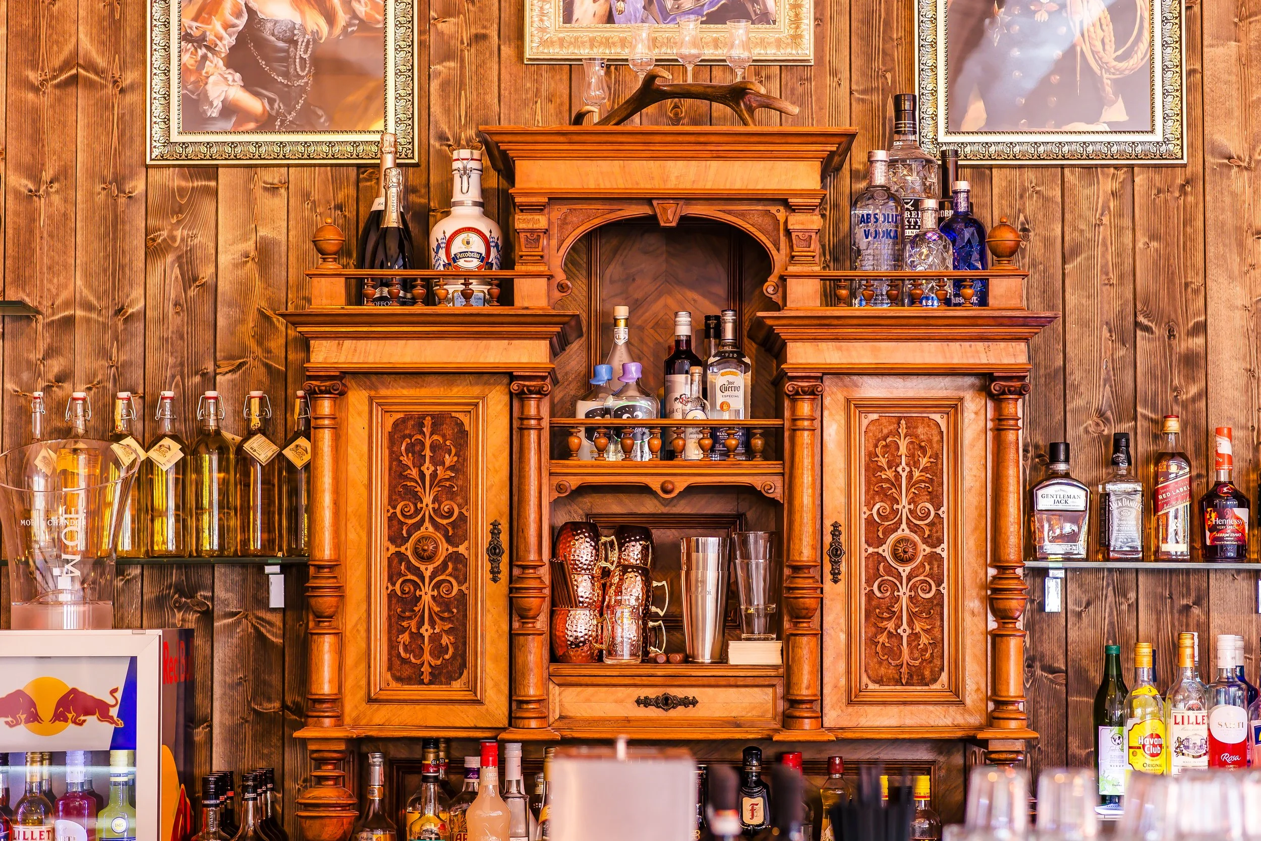 Holzregal mit verschiedenen Spirituosen und Dekorationsartikeln vor einer Holzvertäfelung