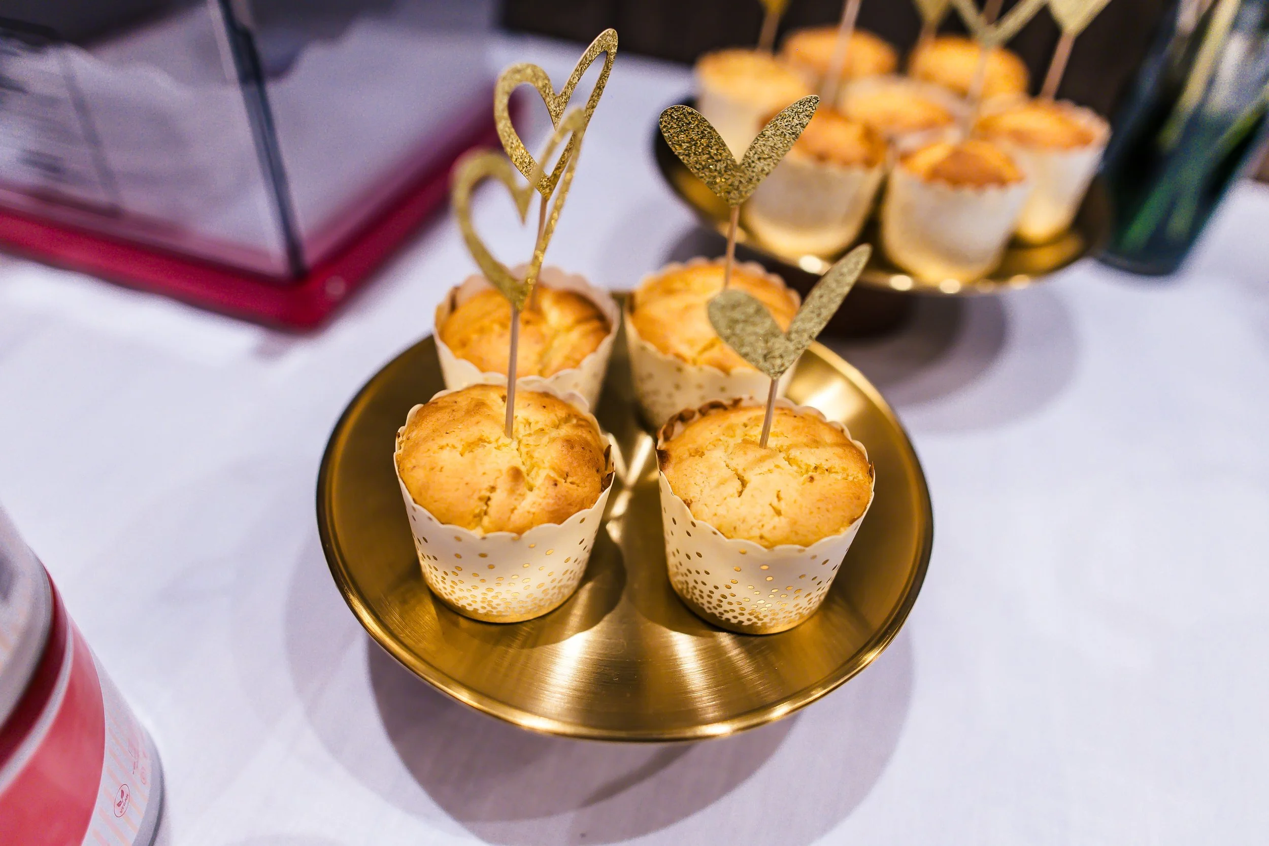Mini-Muffins auf einem goldenen Teller mit goldenen Herz- und Stern-Decorations, im Hintergrund weitere Muffins