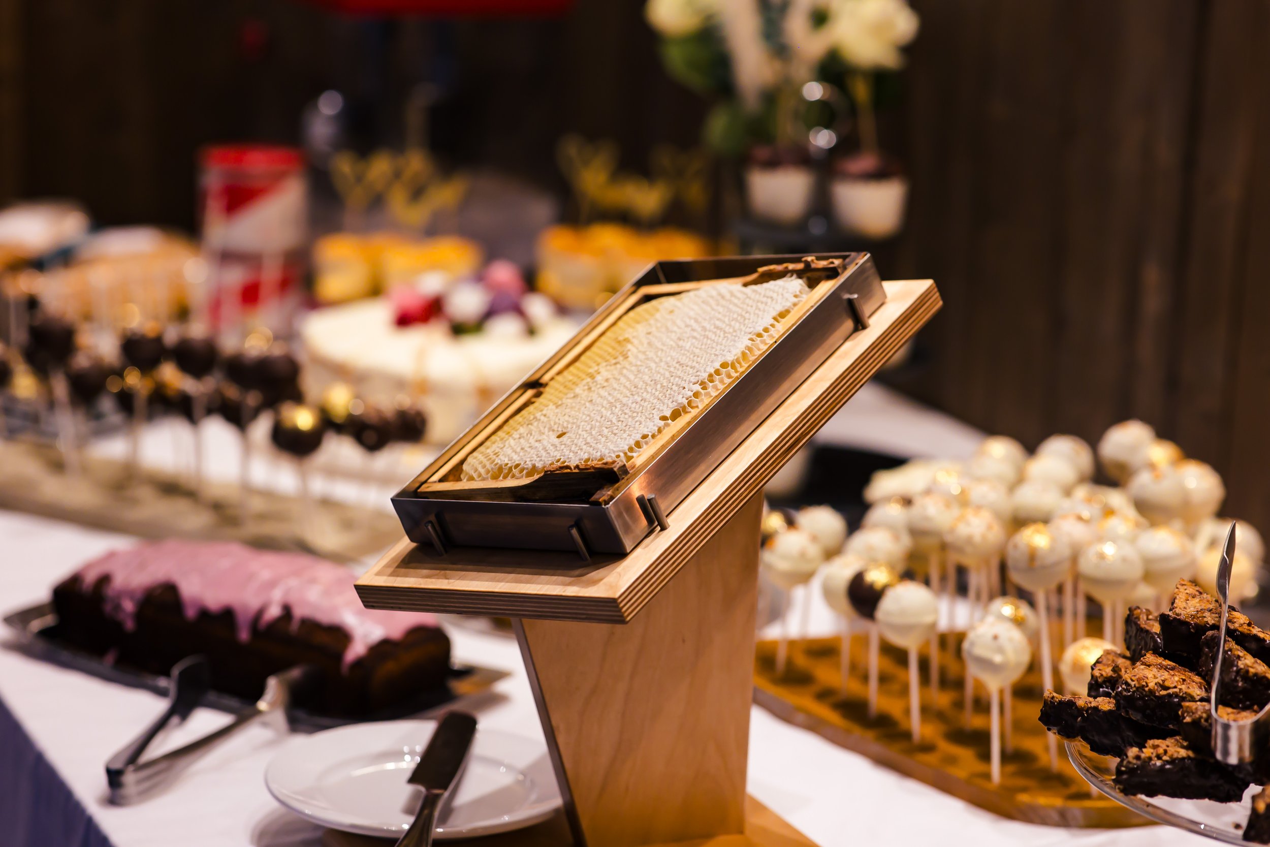 Verschiedene Desserts auf einem Buffettisch, darunter Honigwabe, Kuchen, Cupcakes und Brownies.