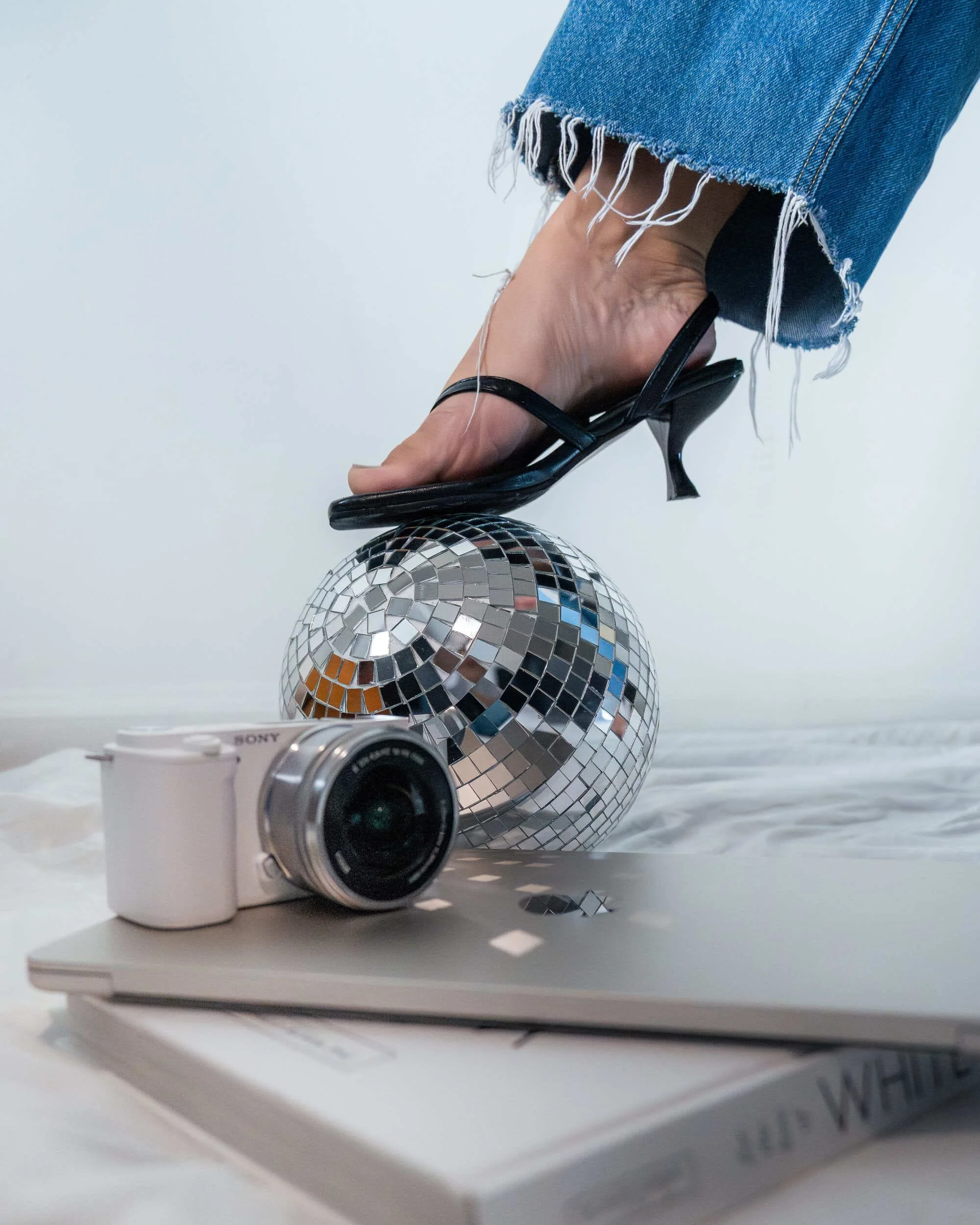 Creative shot of a disco ball balanced on a sandal with a camera below it.