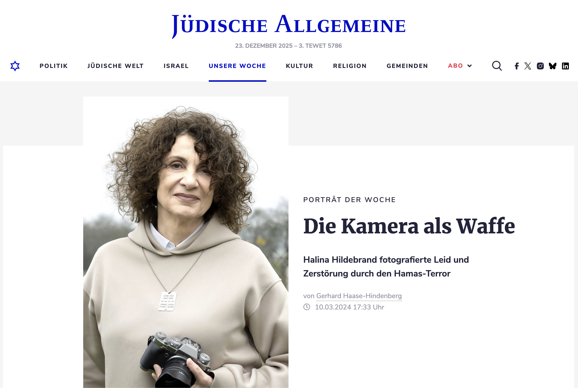 Porträt einer Frau mit lockigem Haar, die eine Kamera hält und eine neutrale Miene zeigt, bei grauem Himmel im Hintergrund.