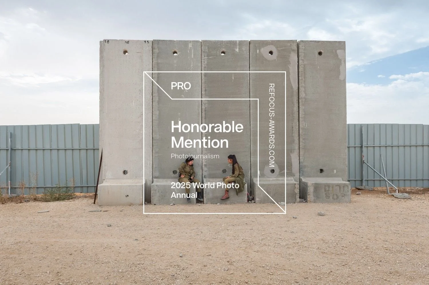 Zwei Frauen sitzen auf einem niedrigen Betonblock vor einem großen Betonwand mit Text, im Hintergrund ein Himmel mit Wolken, eine Metallborte und ein Zaun. Über der Szene liegt ein transparentes Textoverlay mit Informationen zum Fotowettbewerb.