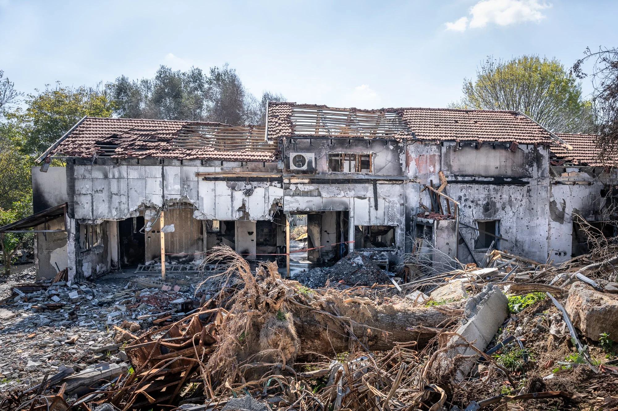 Verbranntes, zerstörtes Haus mit zerbrochenem Dach und Trümmern im Vordergrund.