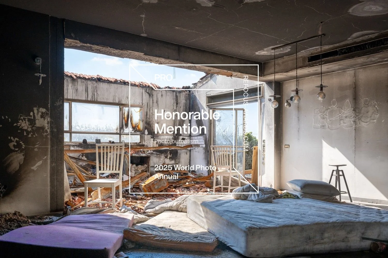 Ein zerstörtes Zimmer mit aufgerissenem Dach, der Himmel ist sichtbar. Das Zimmer ist unordentlich mit einem lagenden Bett, Kissen, Decken, einem Stuhl, einem Hocker und zerbrochenen Fenstern. Sonnenlicht dringt durch die Risse und zerbrochenen Fenster ins Zimmer.
