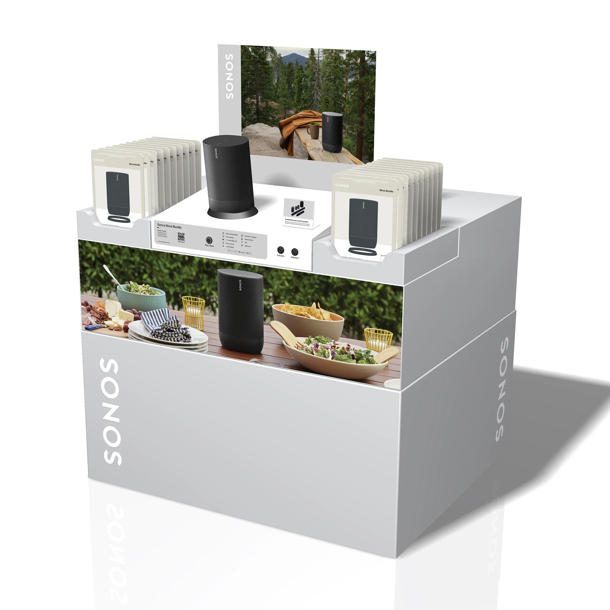Display stand showcasing Sonos speakers and accessories for outdoor use, with promotional images of outdoor and indoor setups, set in a retail environment.