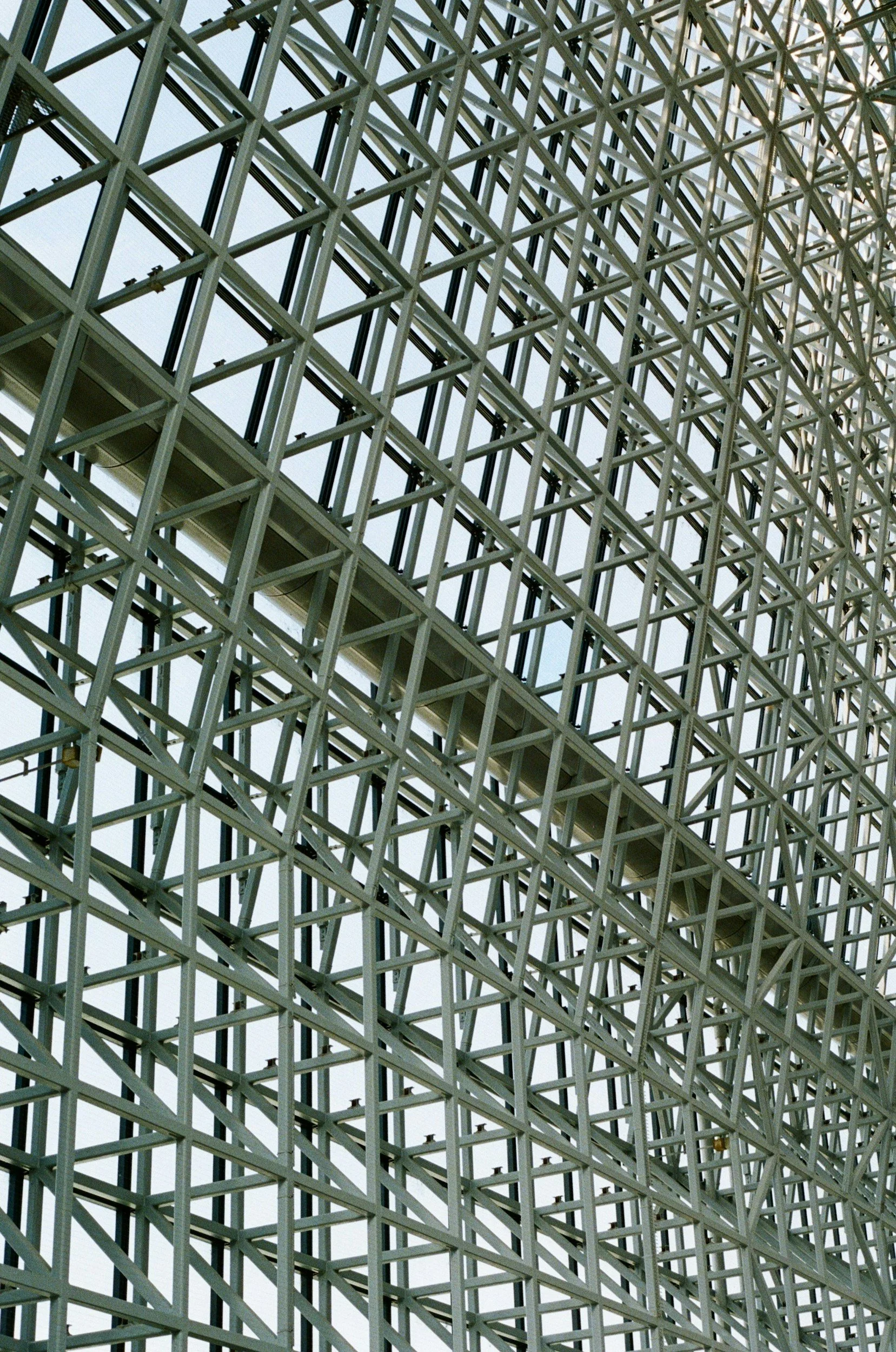 Close-up view of a modern architectural steel framework structure with multiple intersecting beams and glass panels.