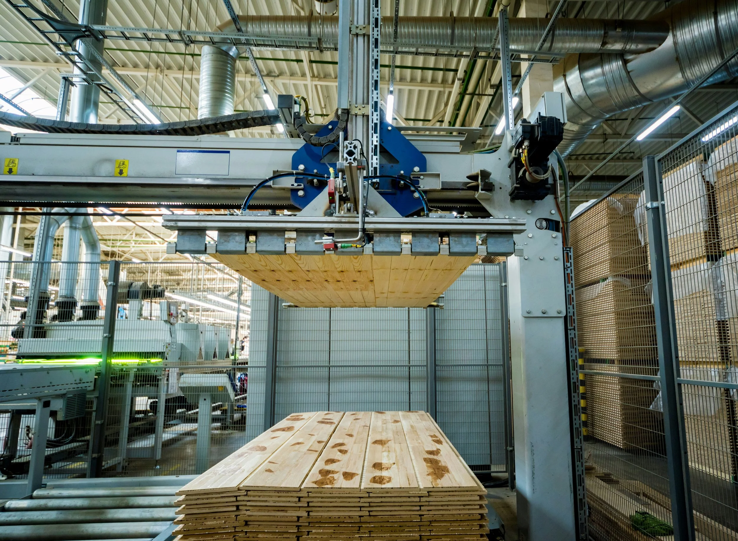 Industrial woodworking machine assembling wooden planks in factory.