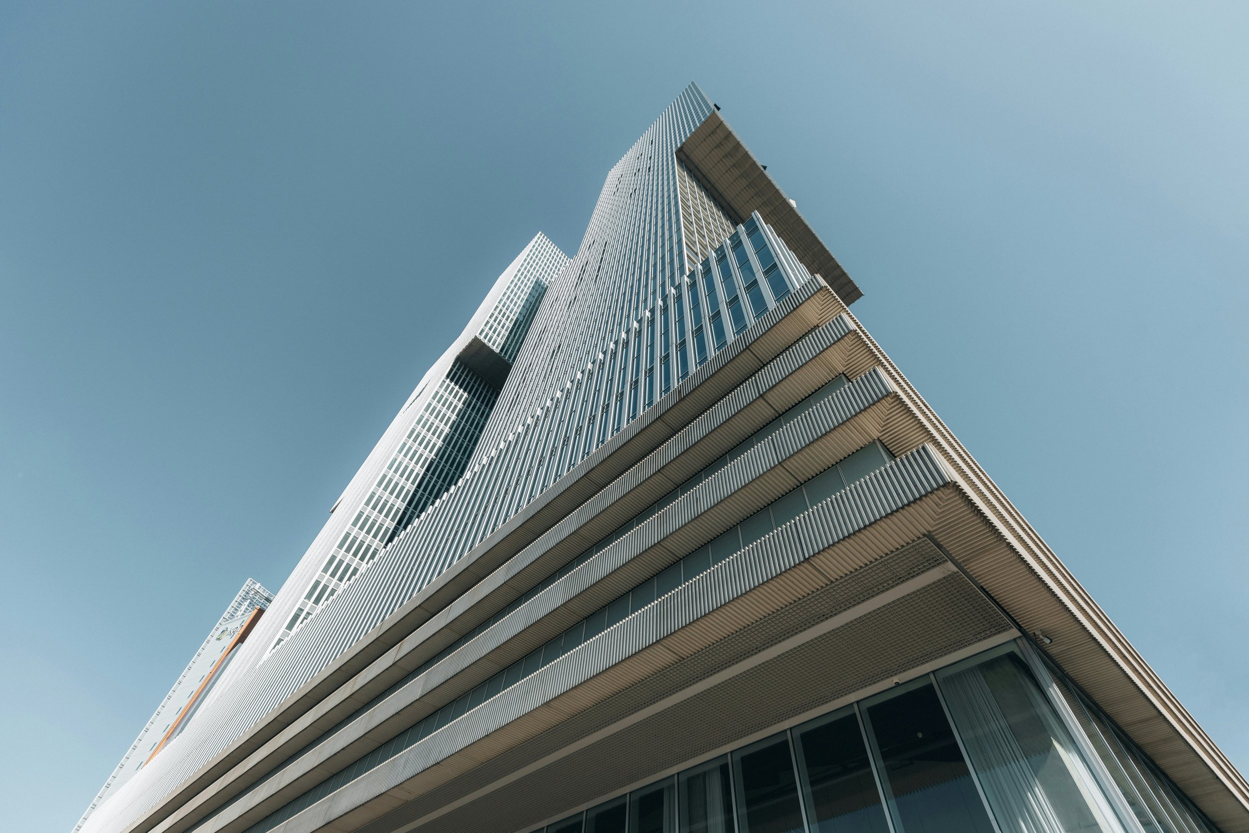 Low-angle view of a modern glass skyscraper against a clear blue sky.