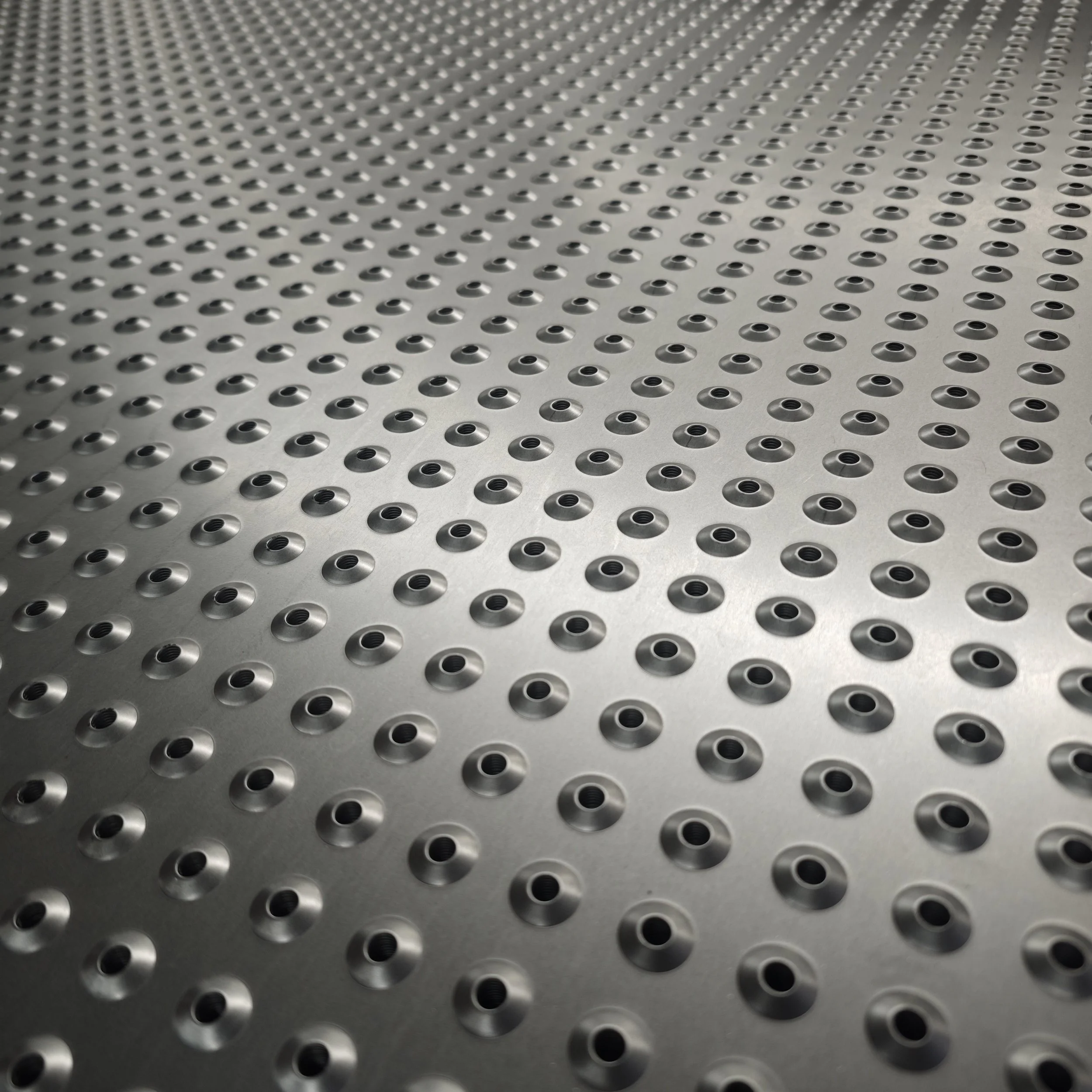 A metallic surface with a pattern of evenly spaced, round holes.