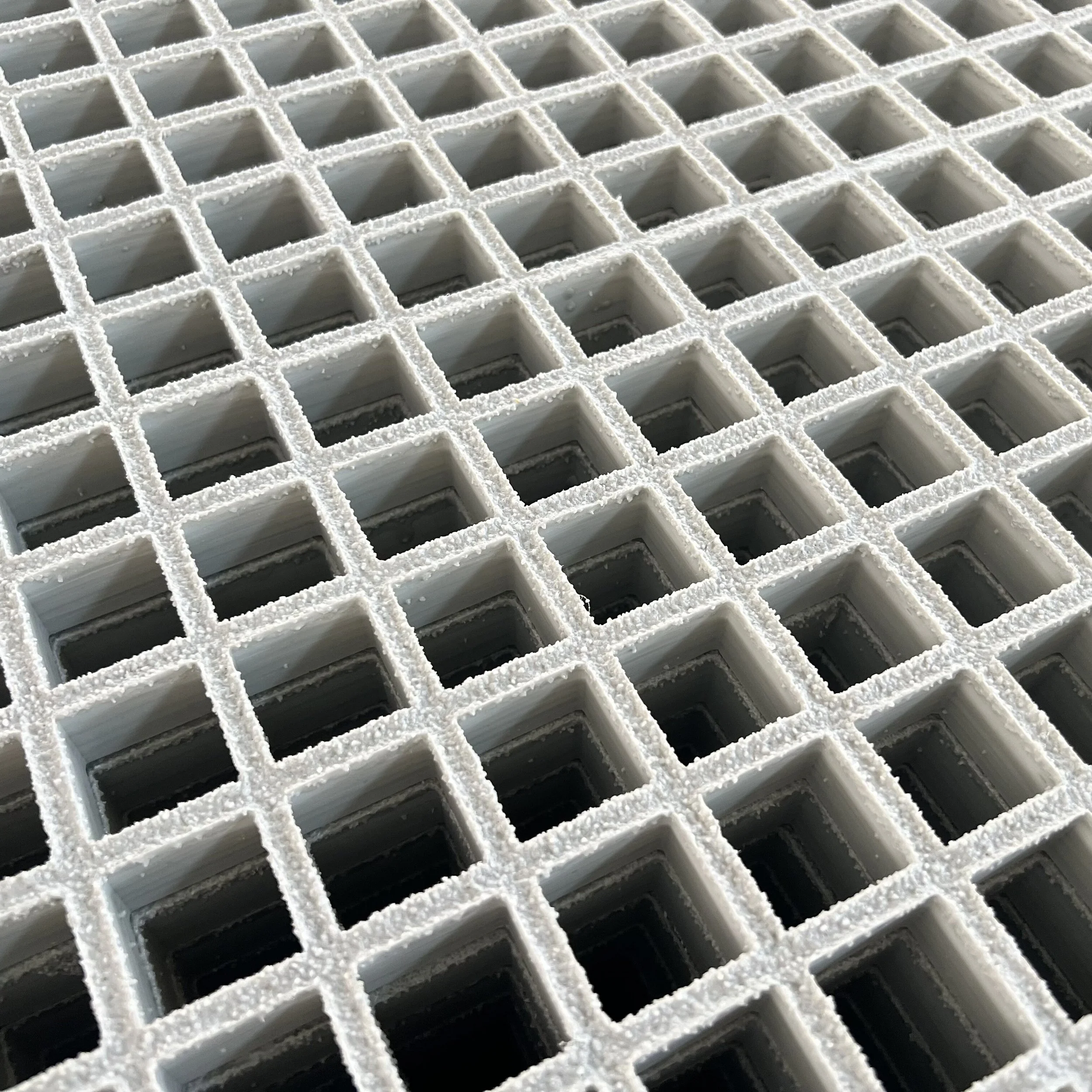 Close-up of a white plastic grid with square openings, some of which are coated with salt crystals.
