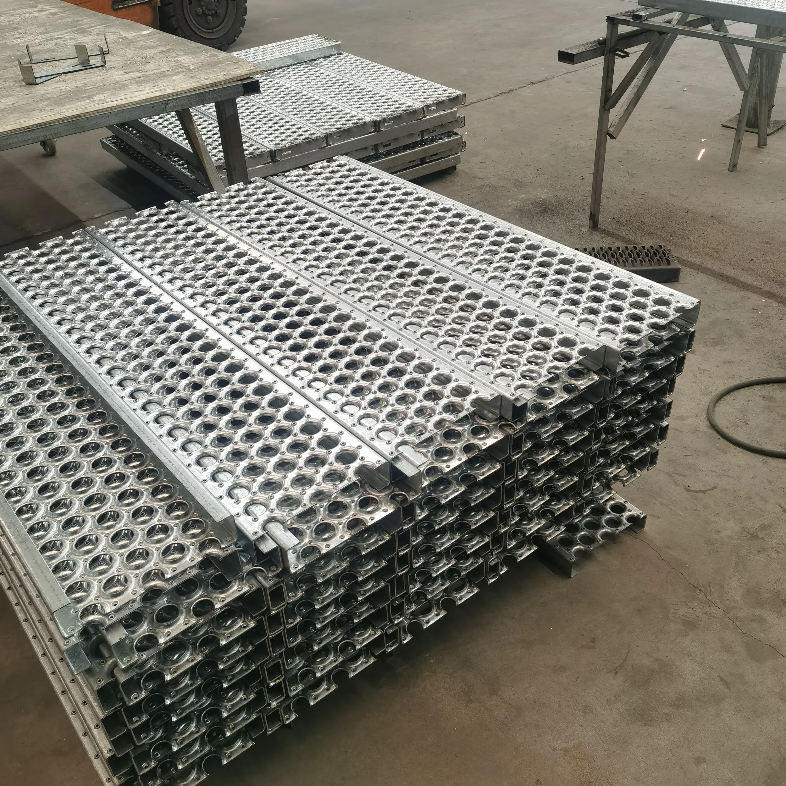 Stacked metal components with circular holes in a factory or workshop setting.