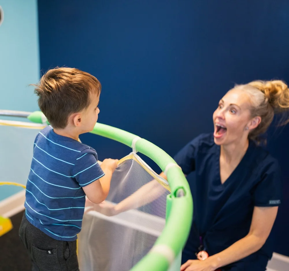 A StarBright Centers therapist and a child laughing together at the sensory gym trampoline in Maryville, TN