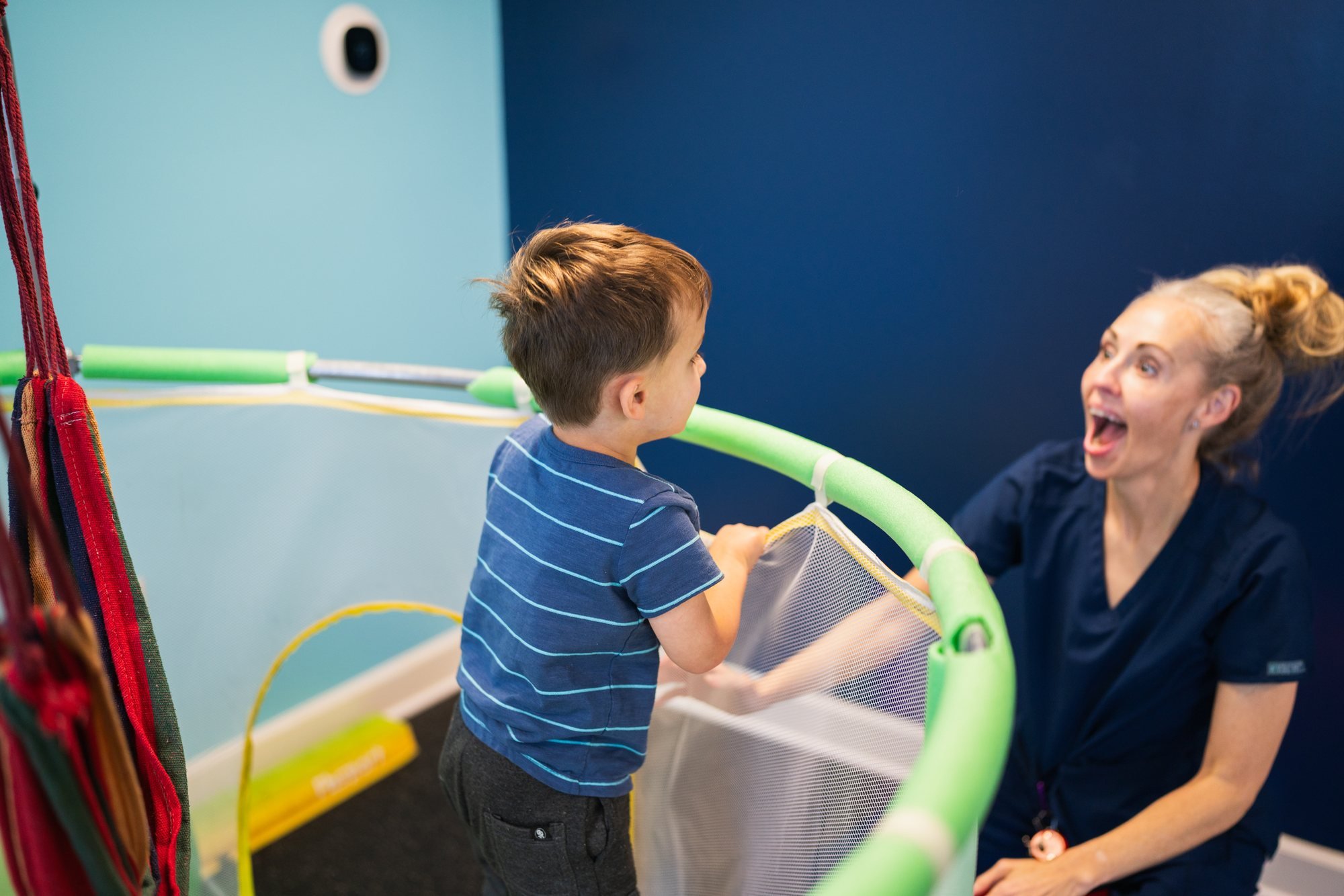 Therapist cheering on a child at the trampoline in the StarBright Centers sensory gym