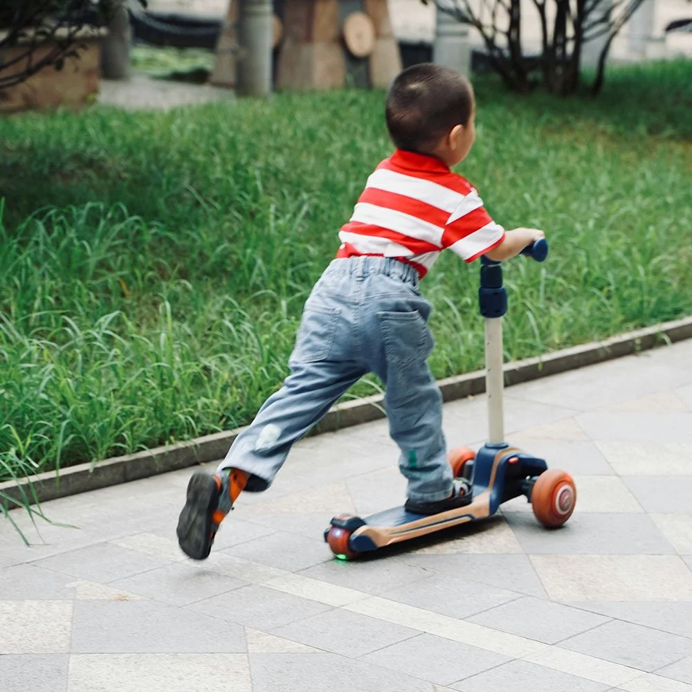 Small child in a red white stripe shirt, riding a scooter.