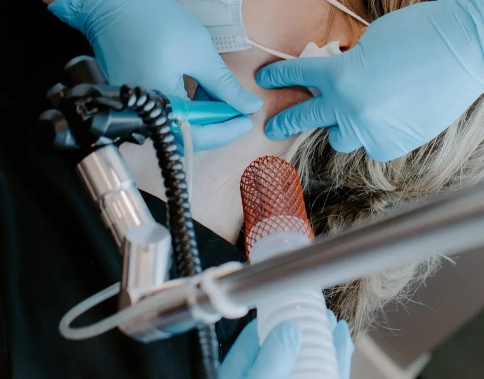Close-up of a medical team performing a surgical procedure on a patient's face, with medical instruments and a breathing mask visible.