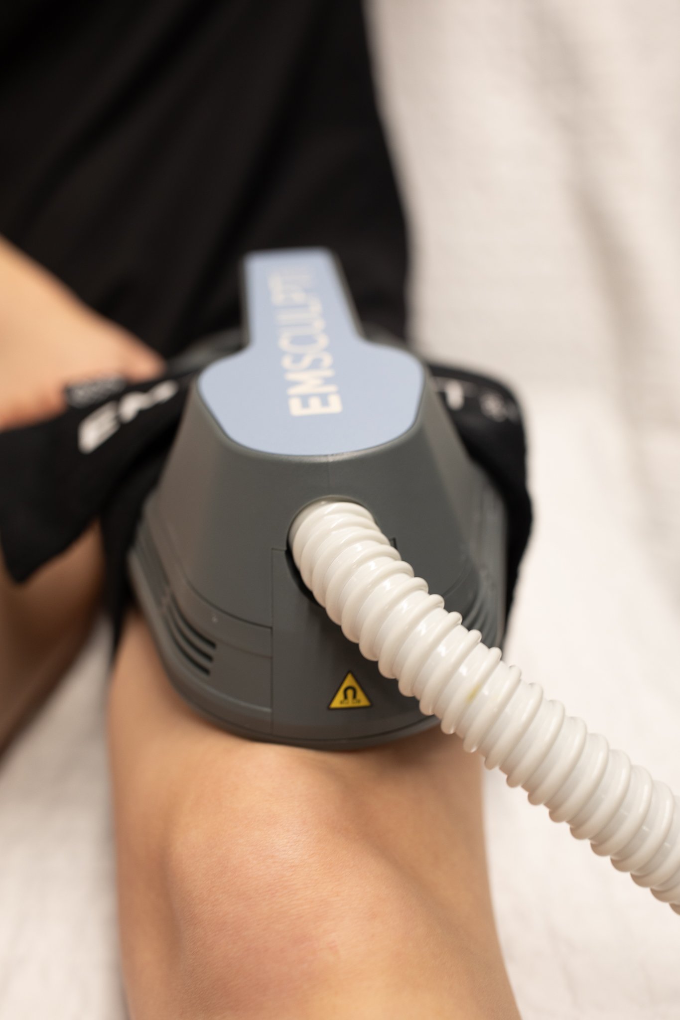 Close-up of a medical device attached to a person's knee, with a white corrugated tube connected to the device, which has a warning label and the word 'ENOSURF' printed on it.