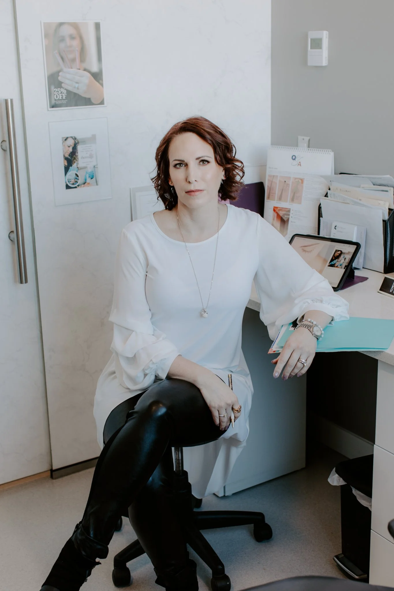 Woman in a white blouse seated at a desk in a medical office