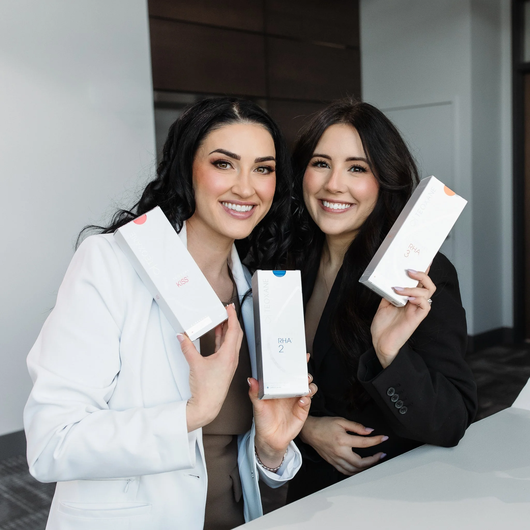 Two women holding skincare product boxes and smiling at the camera.