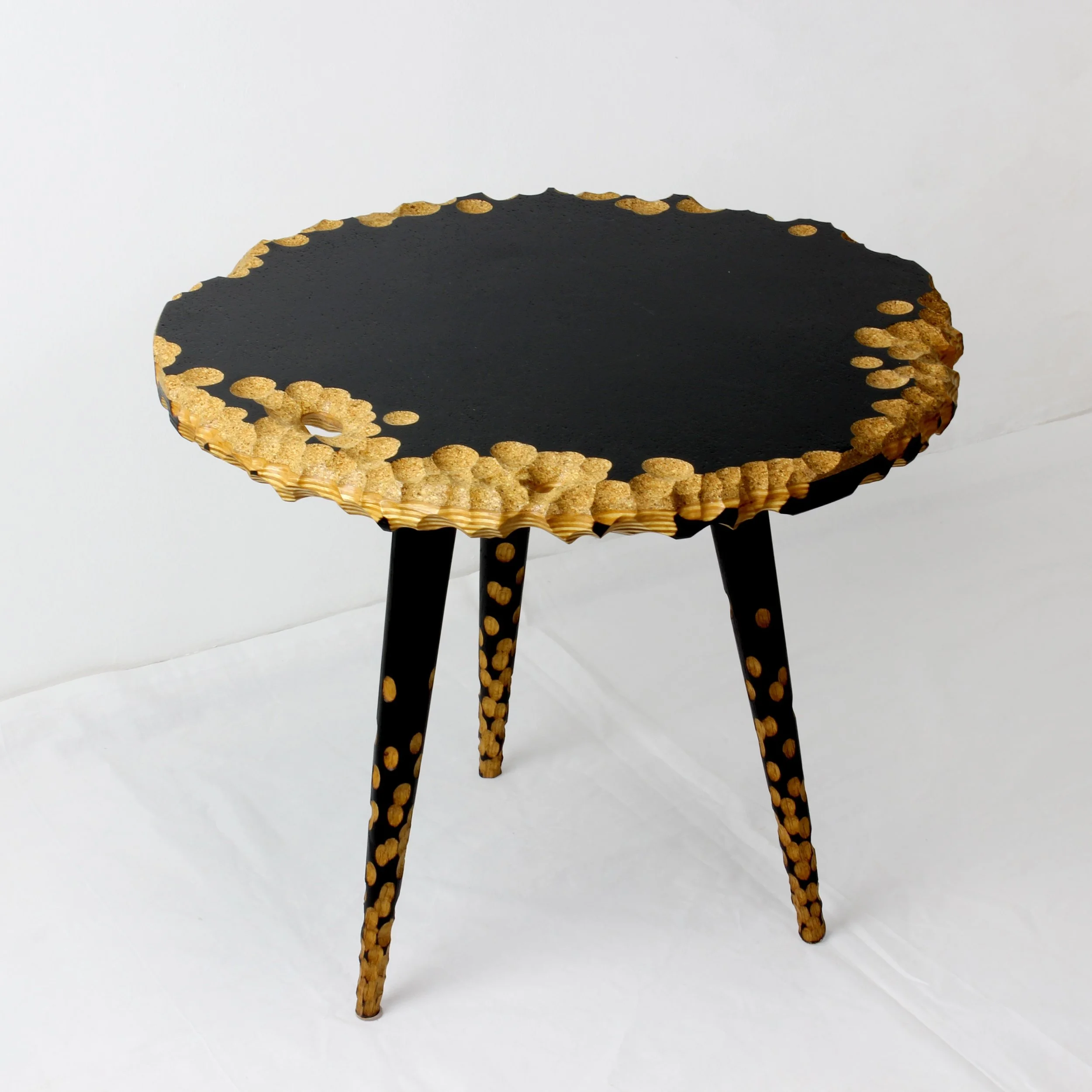 A black round table with gold circular accents along the edge and on the three legs, set against a plain white background.